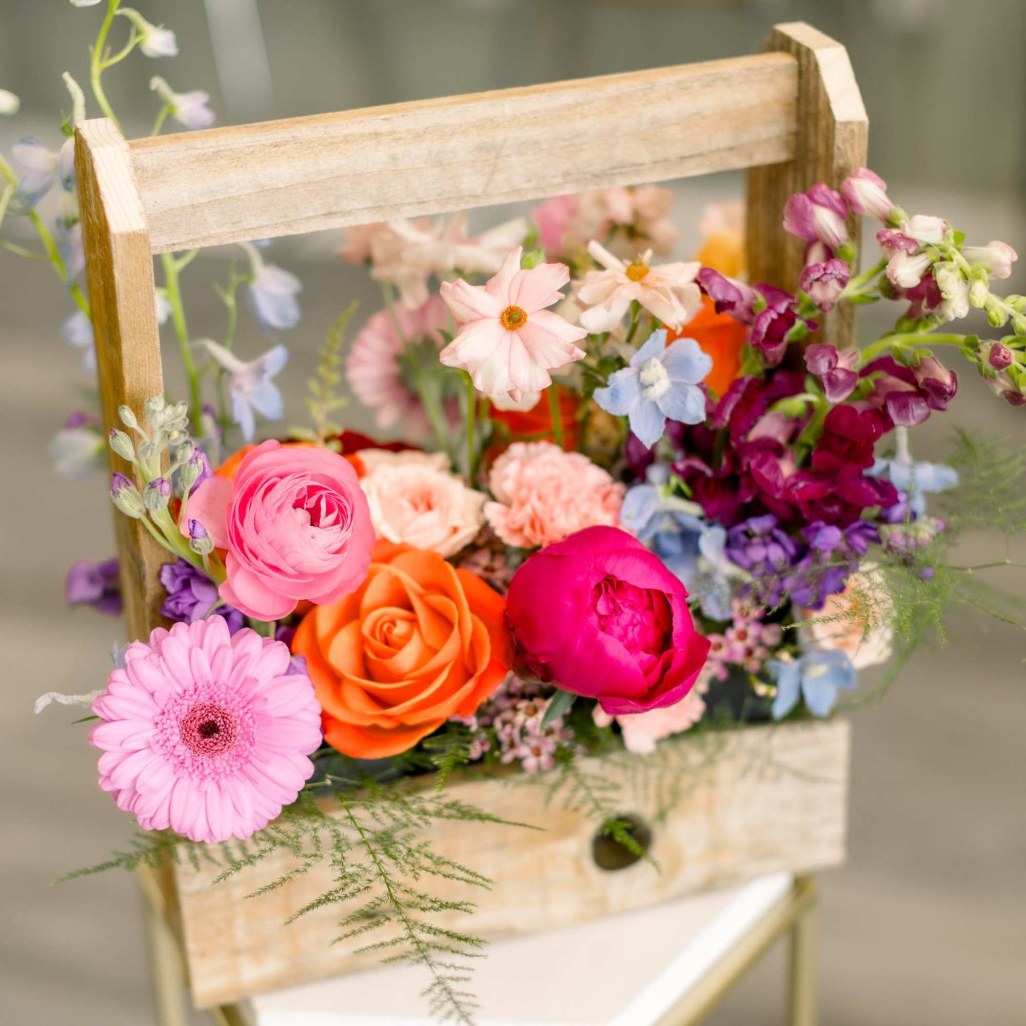 Colorful mixed flowers arranged in a small wooden basket
