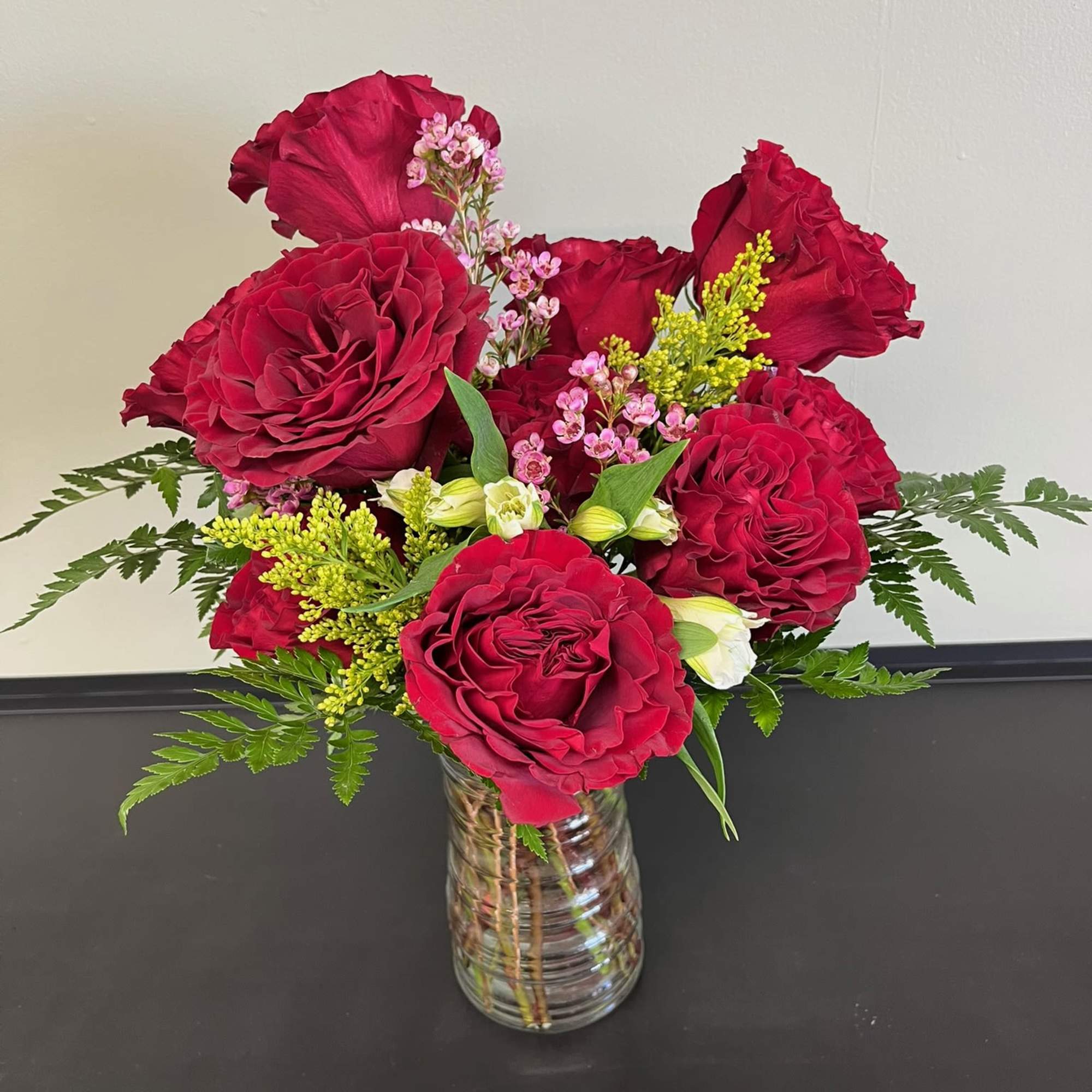 Red rose bouquet in a clear glass vase with small pink accent flowers