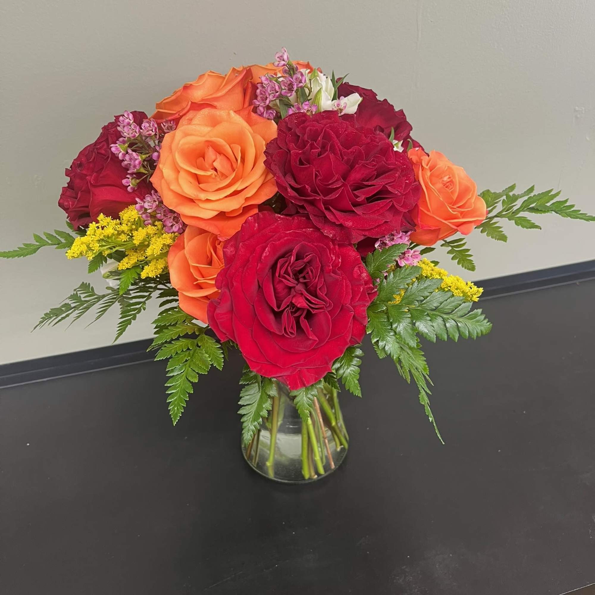 Bouquet of red and orange roses in a clear glass vase