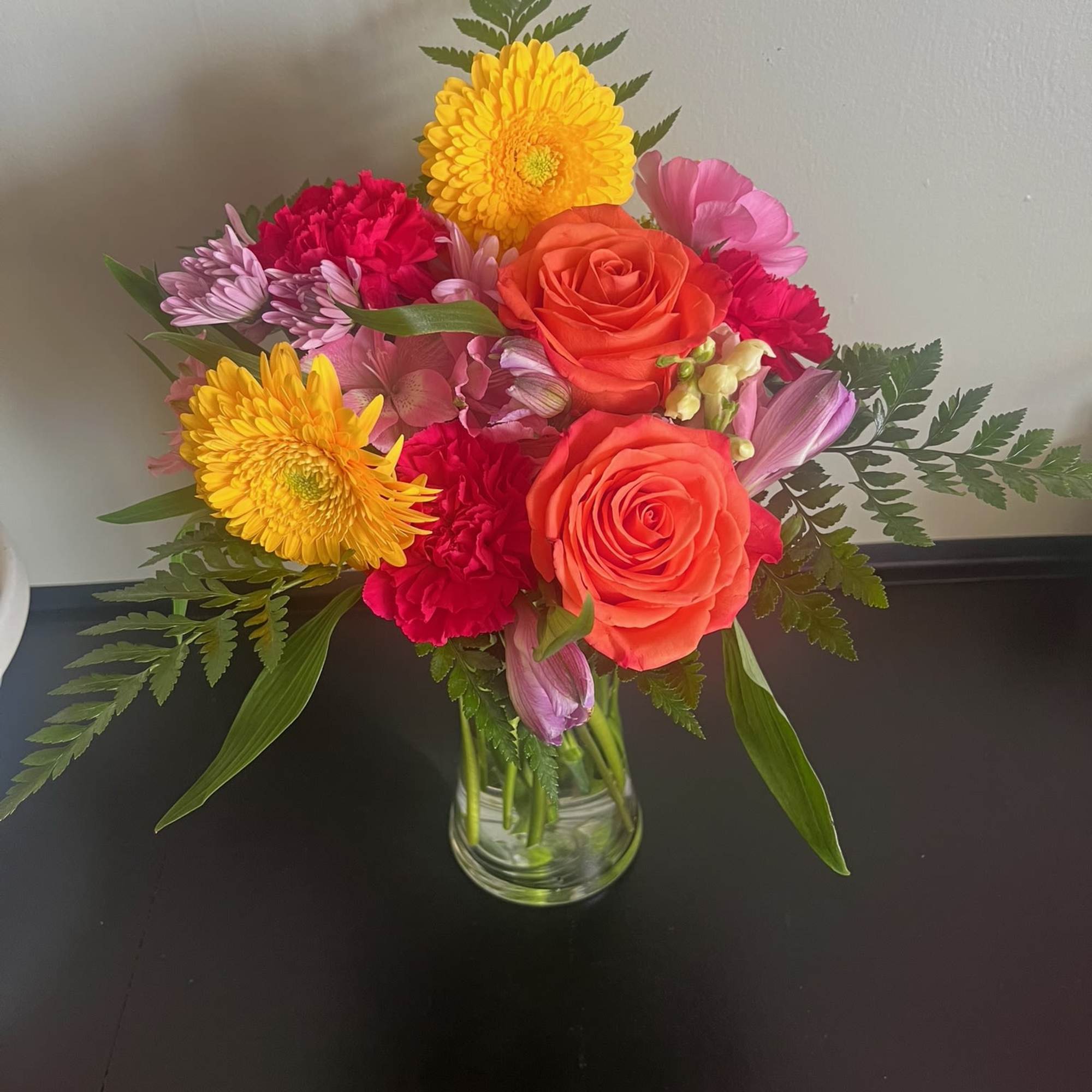 Mixed bouquet of roses, chrysanthemums, and carnations in a glass vase