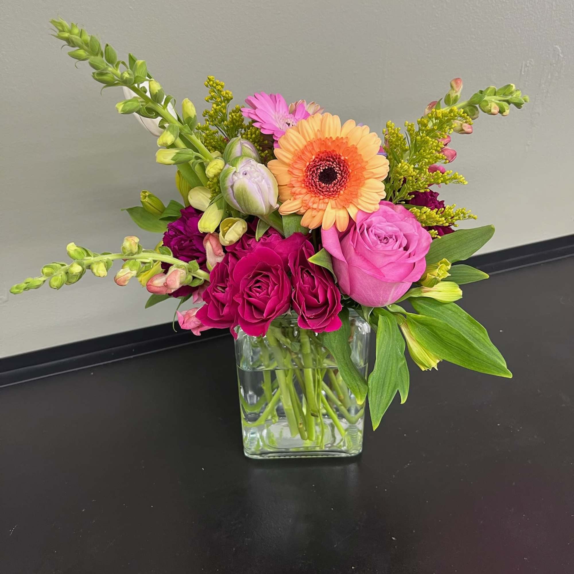 Mixed bouquet in a clear glass vase with pink and orange blooms