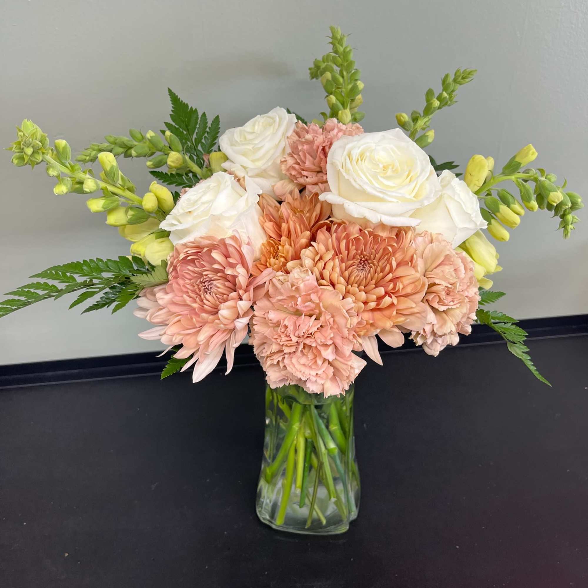 Peach and white bouquet in a clear glass vase