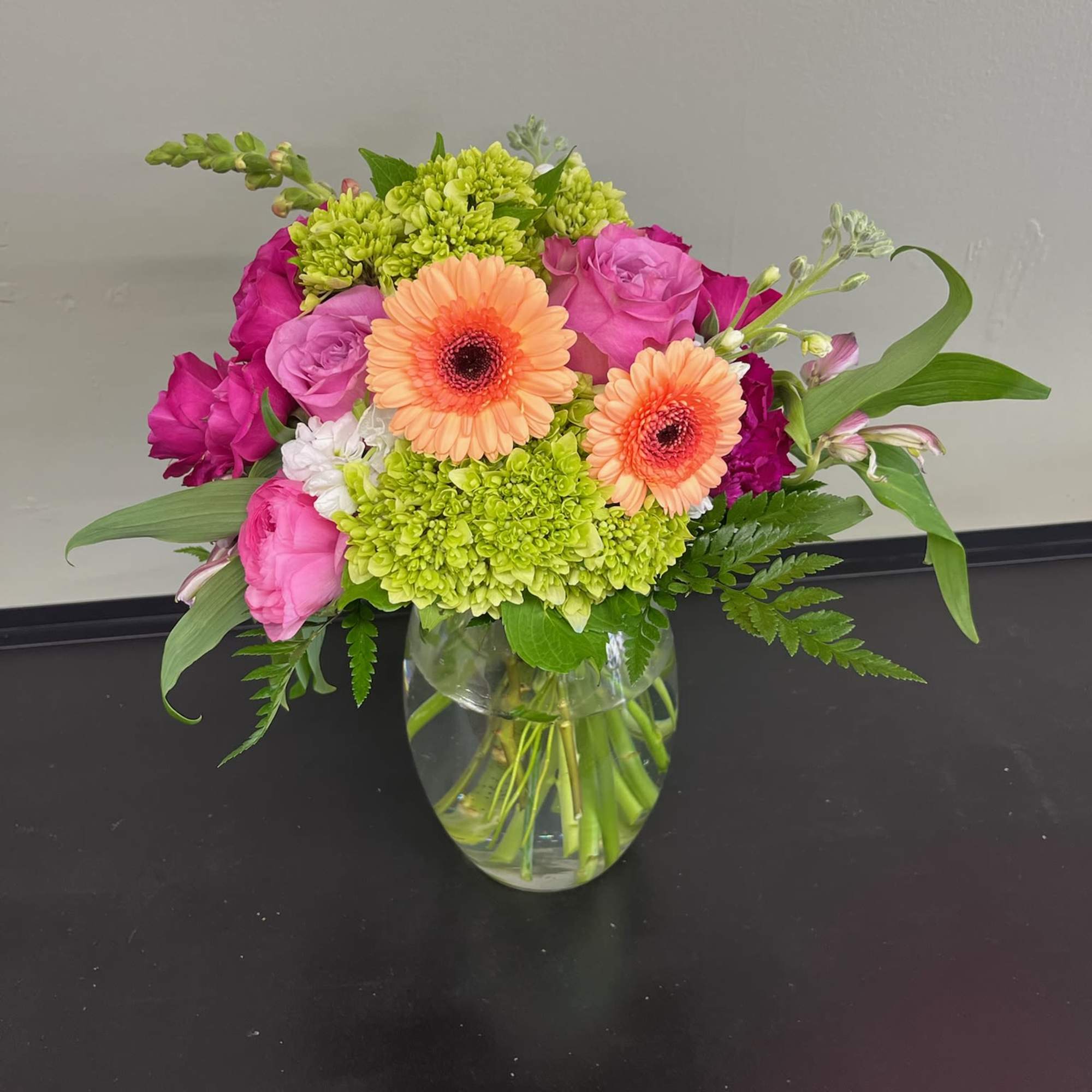 Mixed pink and peach flowers arranged in a clear glass vase