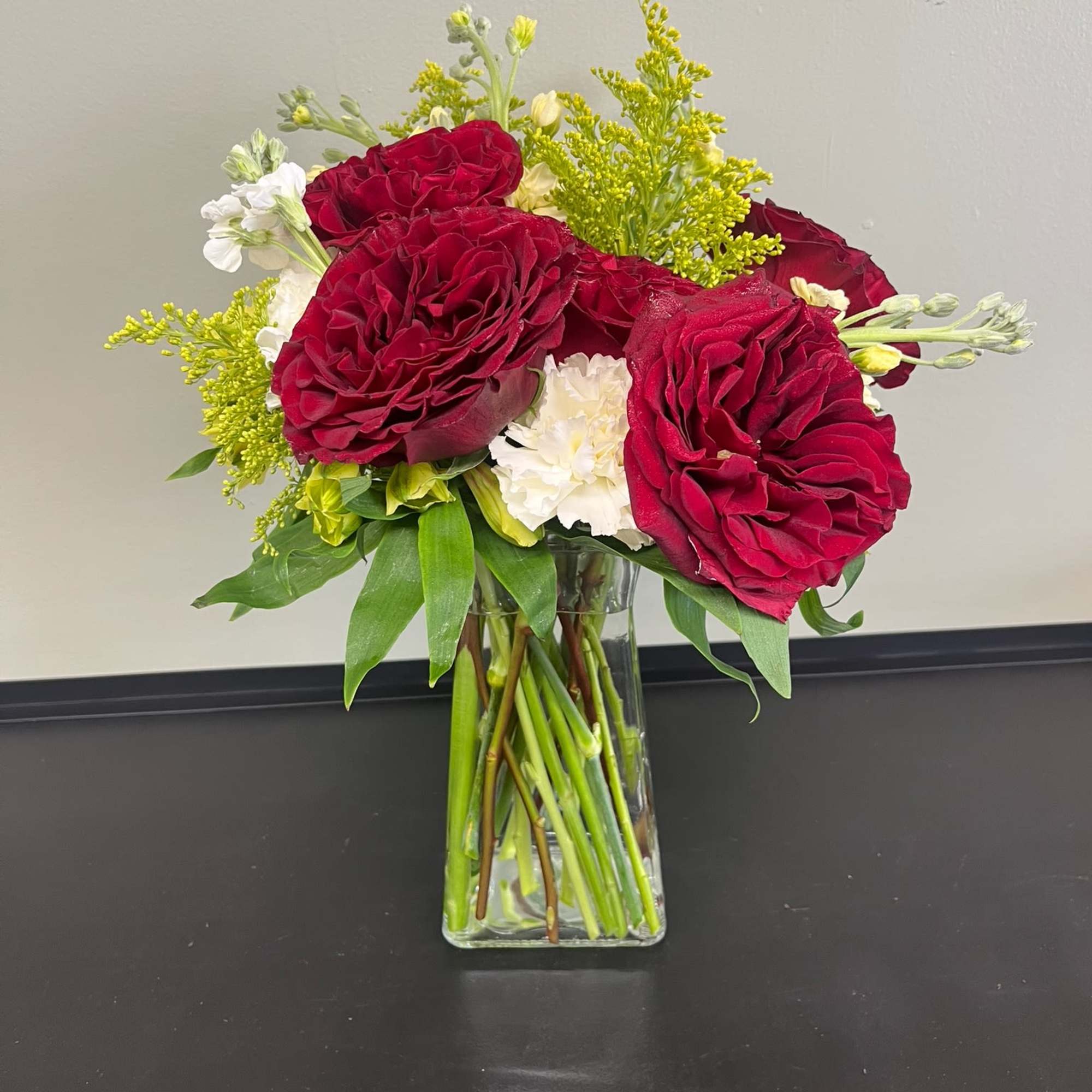 Red roses and white flowers arranged in a clear glass vase