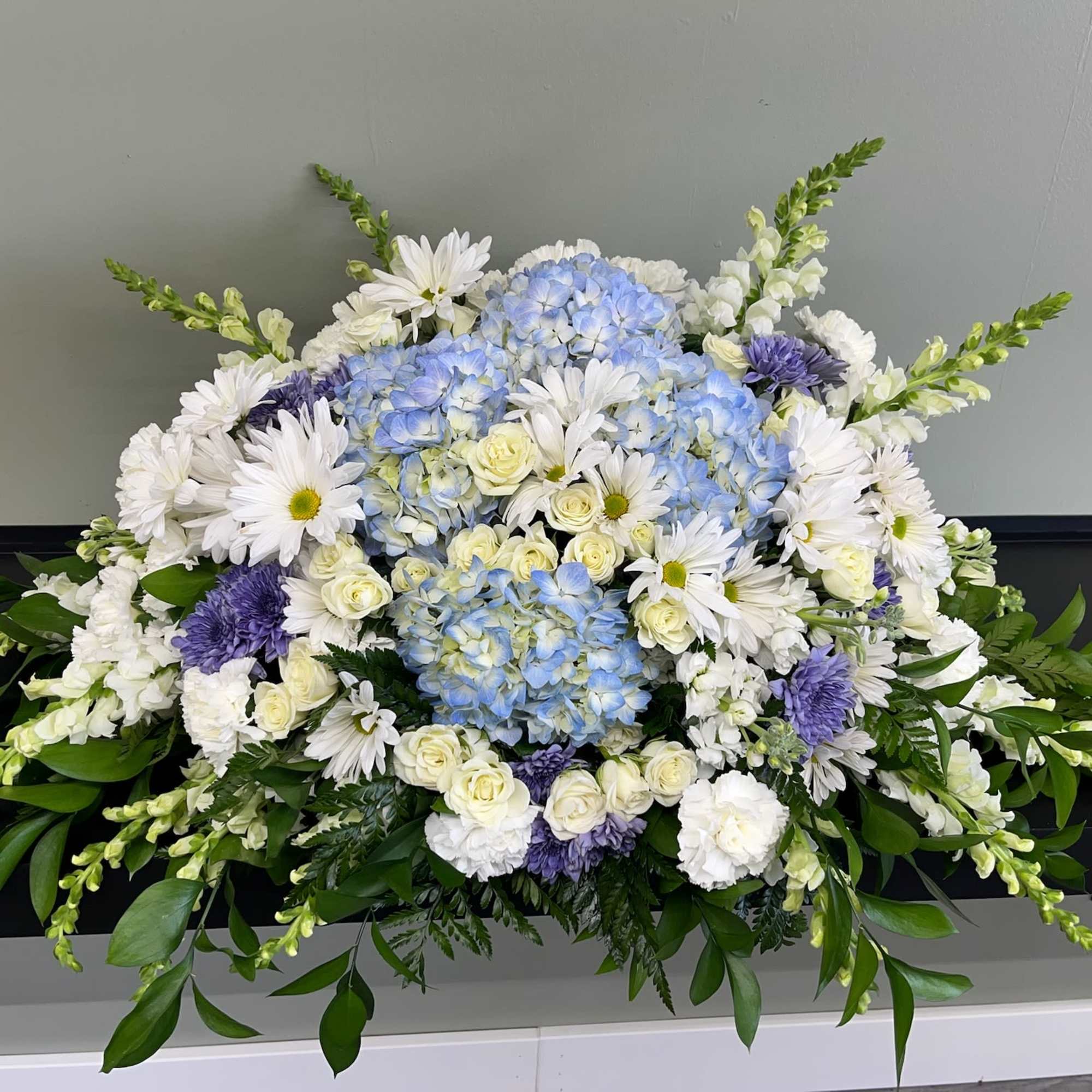 Large white, blue, and purple floral arrangement with daisies and hydrangeas