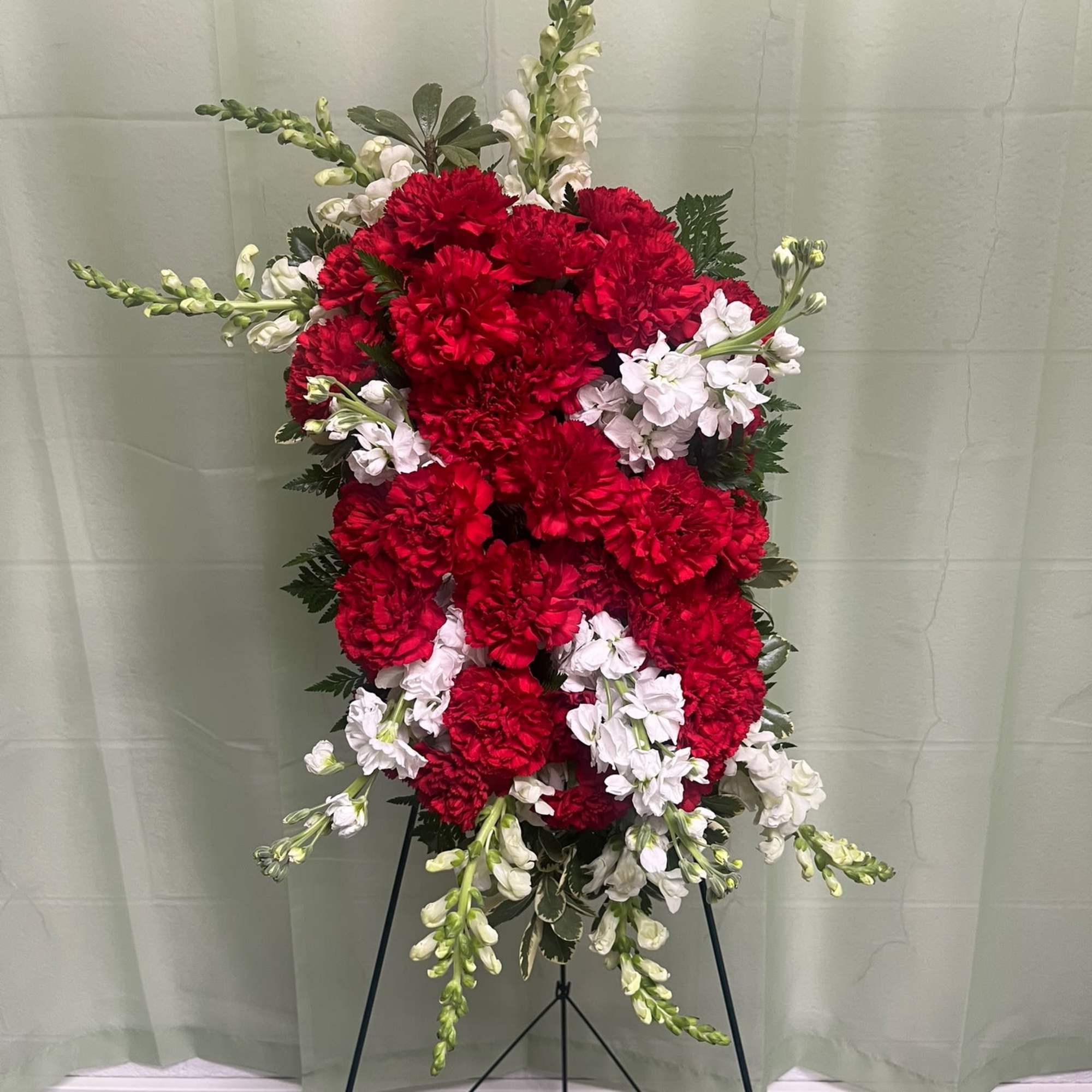 Standing floral spray of red and white carnations on a black easel