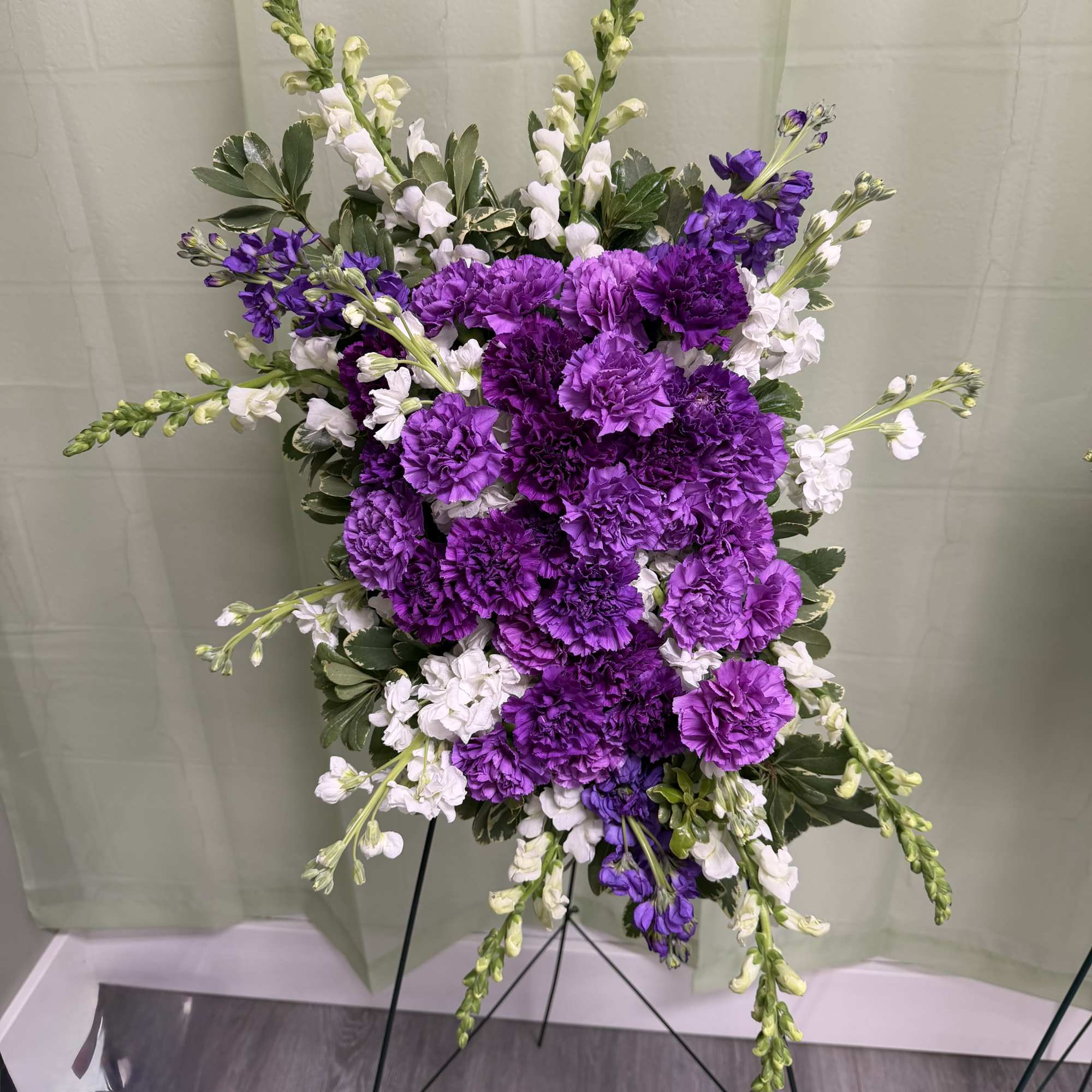 Purple and white floral standing spray on a metal easel