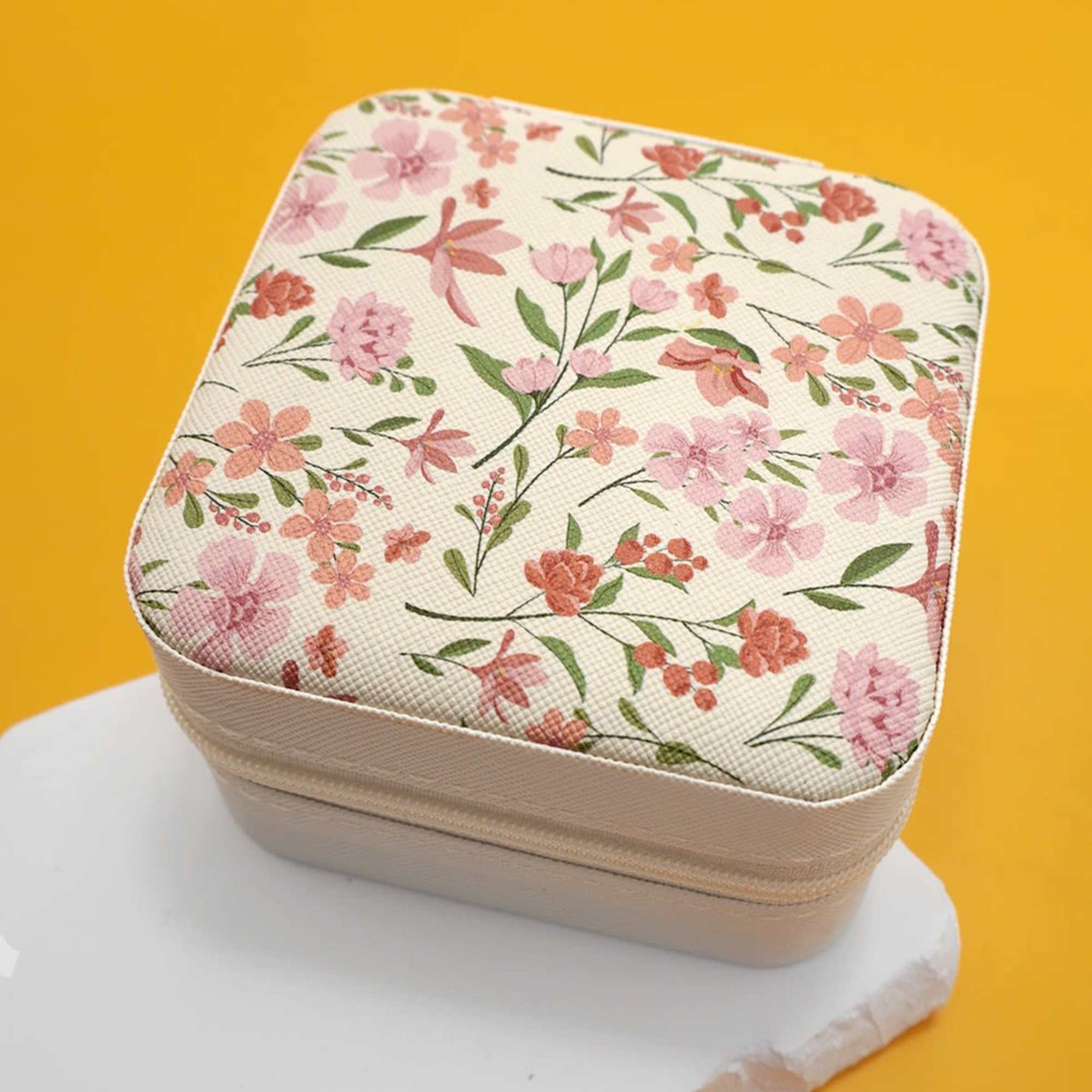 Floral-patterned square zippered case on a yellow background