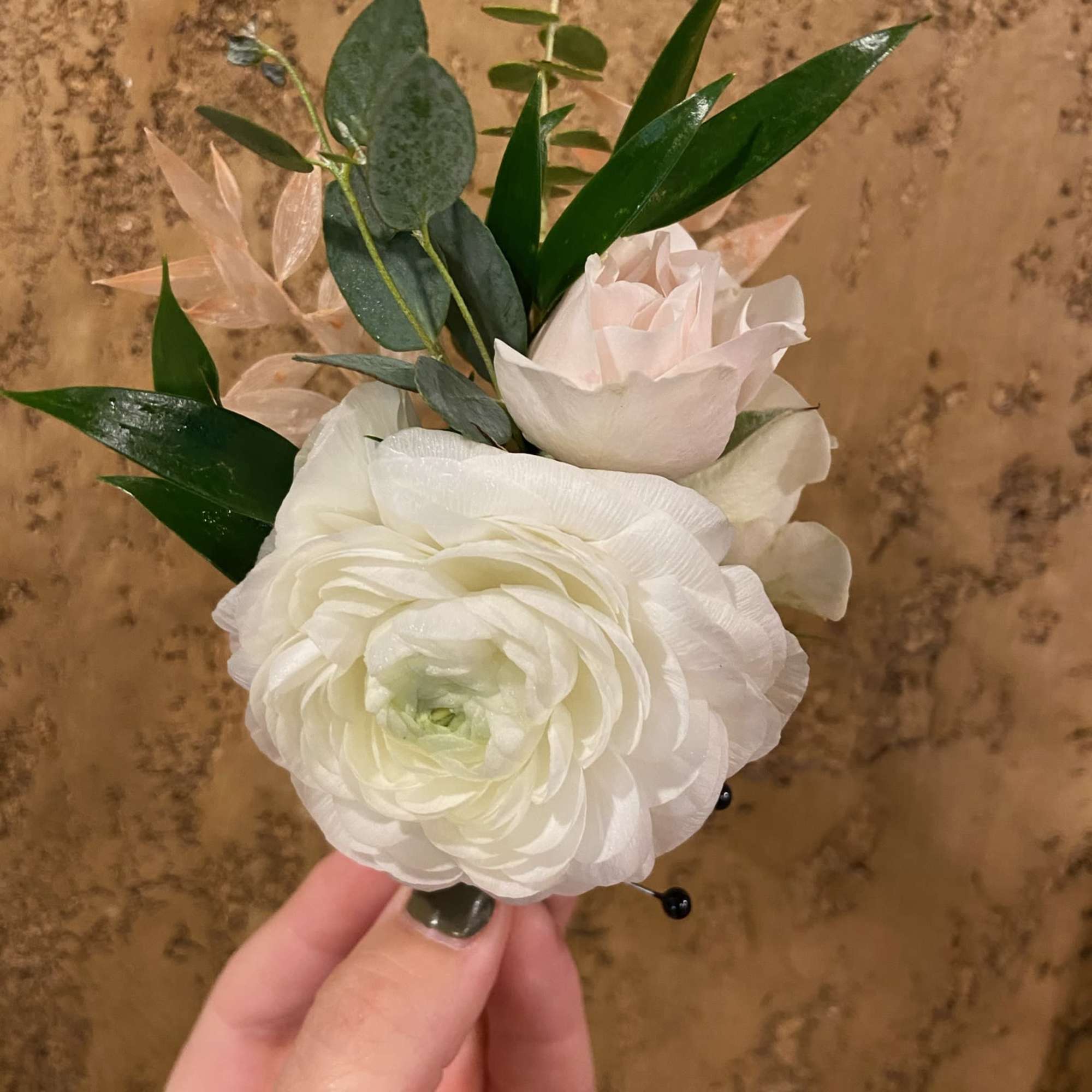 Small white floral boutonniere with greenery and pale pink accents