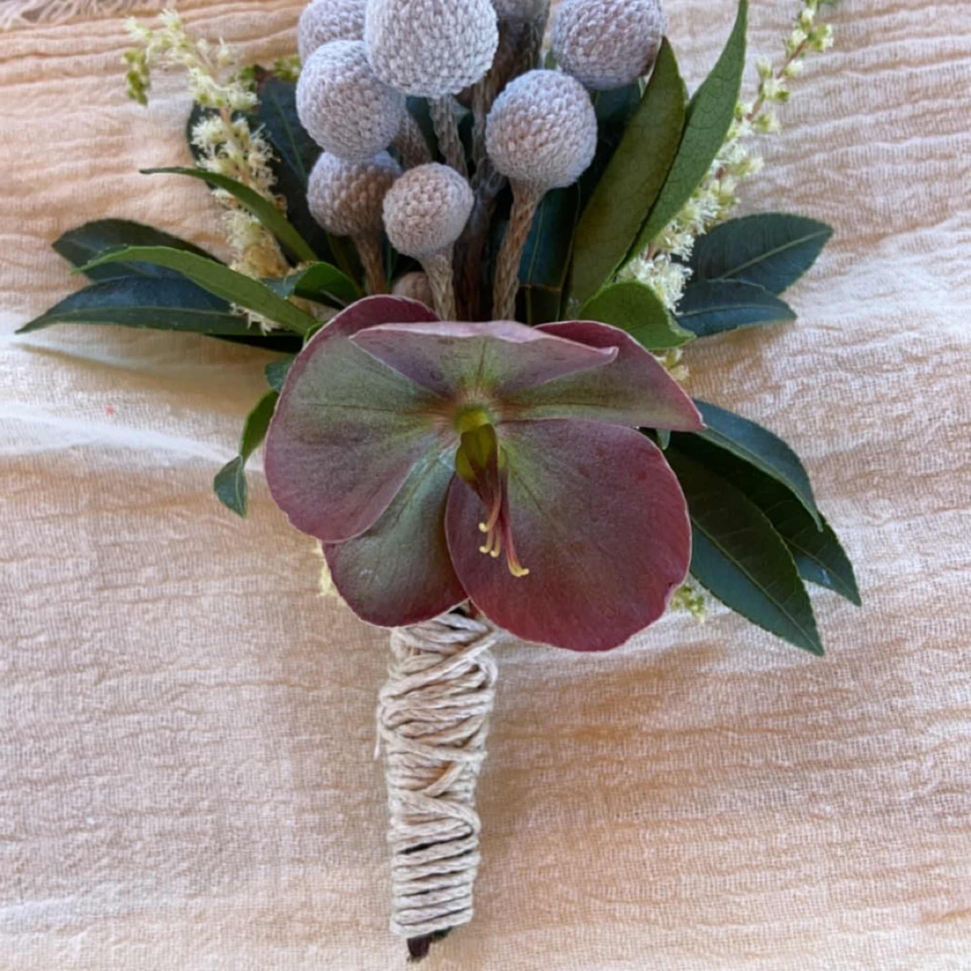 Small boutonniere with a burgundy flower and pale gray seed pods