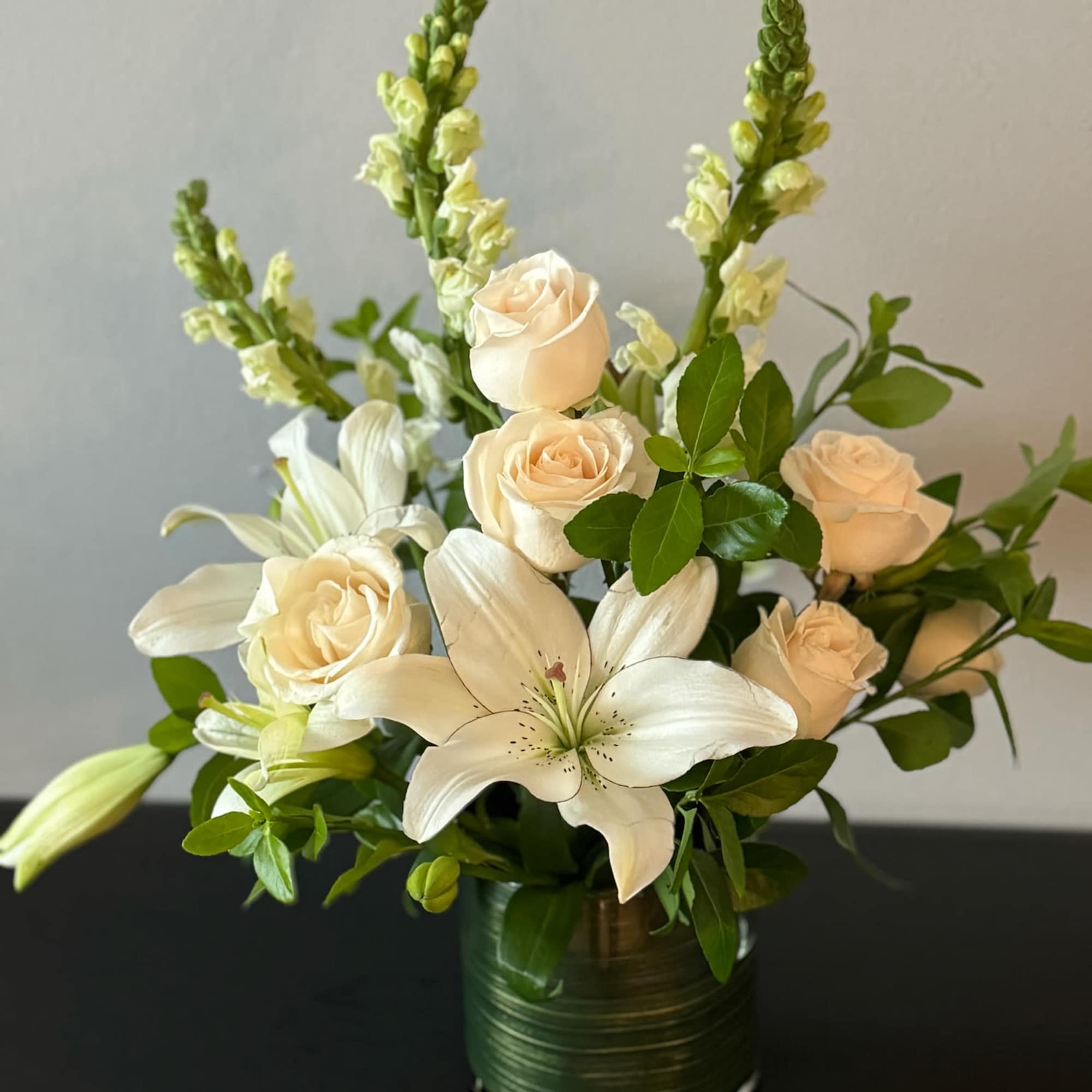 White lilies and cream roses in a green vase