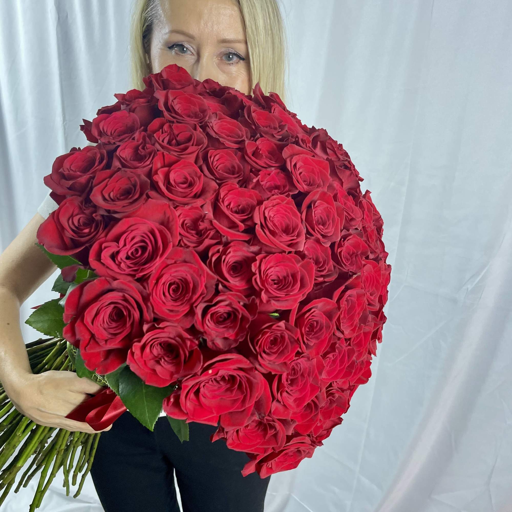Woman holding a large bouquet of red roses