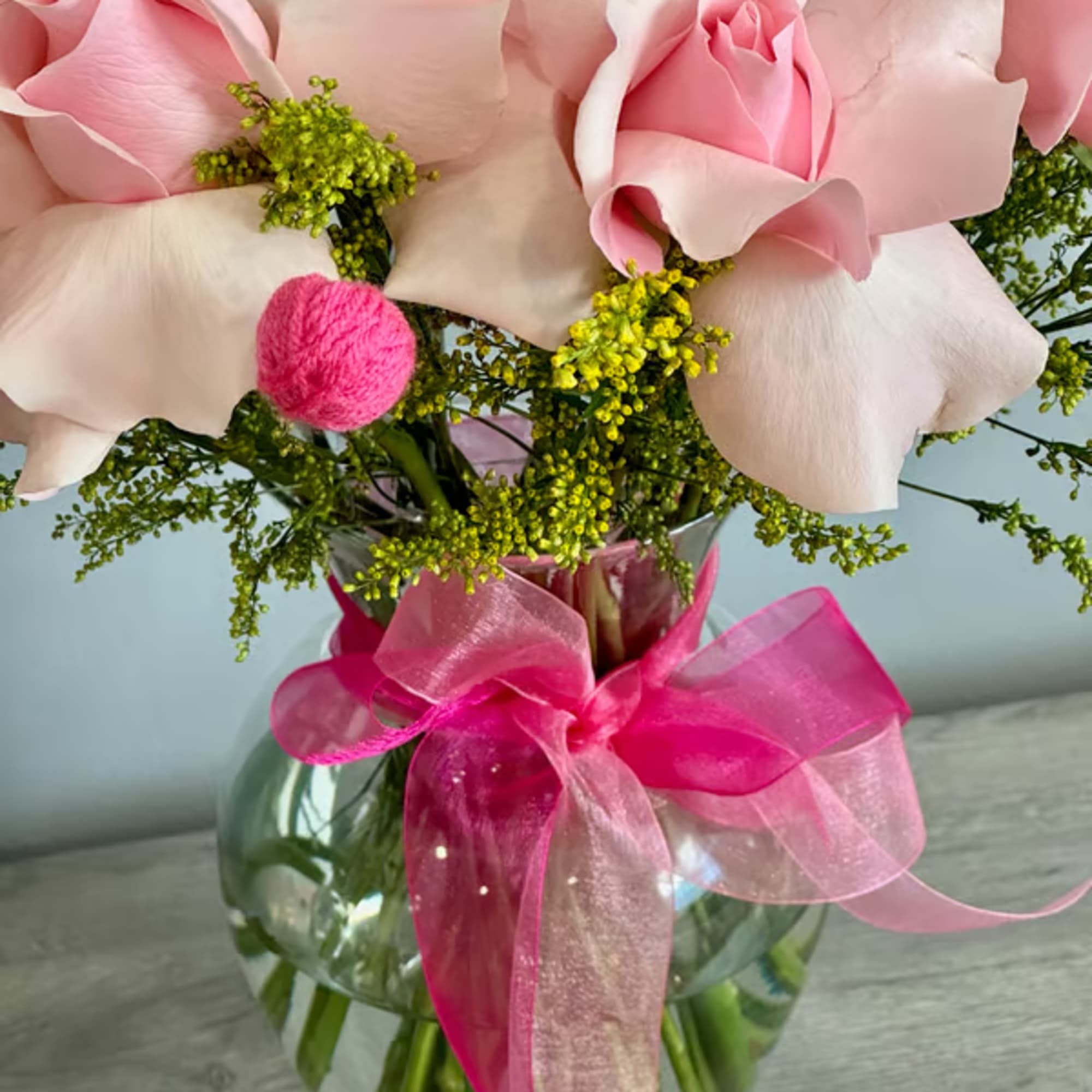 Pink calla lilies in a glass vase with a bright pink ribbon