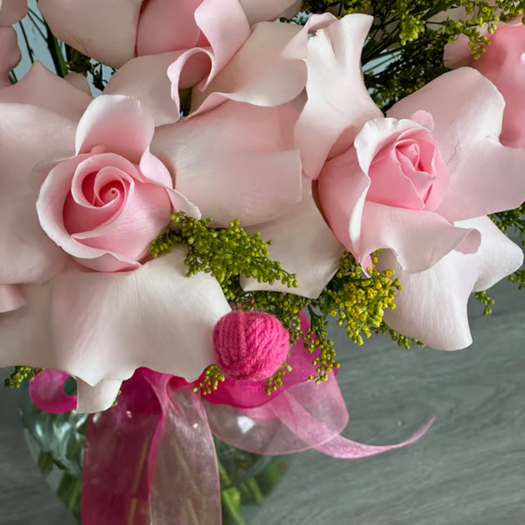 Pink roses and white calla lilies in a glass vase with a pink ribbon