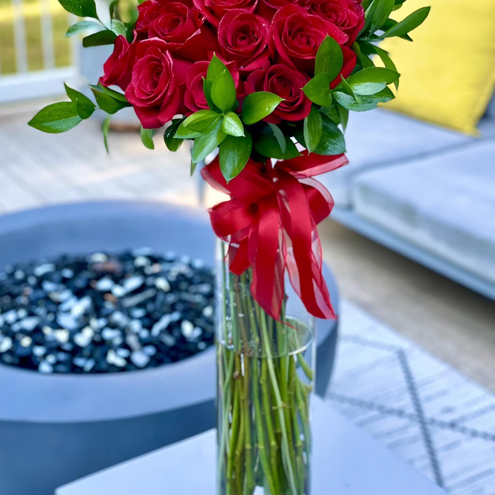 Red rose bouquet in a tall glass vase with a red ribbon