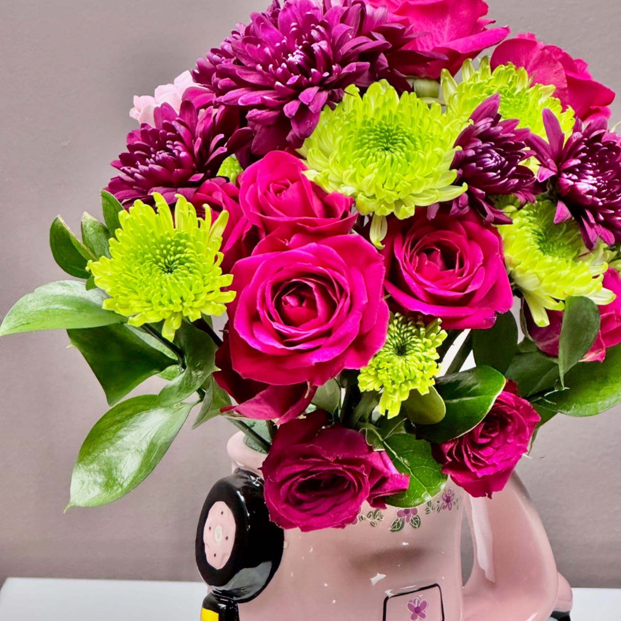 Bouquet of hot pink roses and lime green chrysanthemums in a pink mug vase