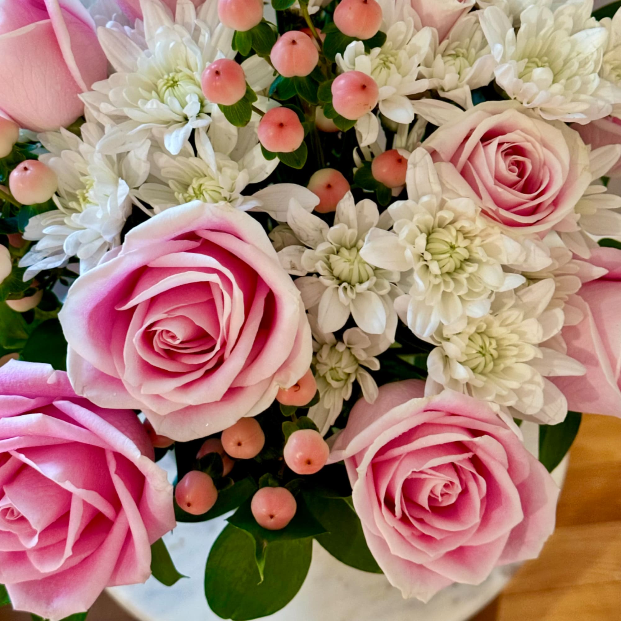 Pink roses with white chrysanthemums and small pink berries in a bouquet