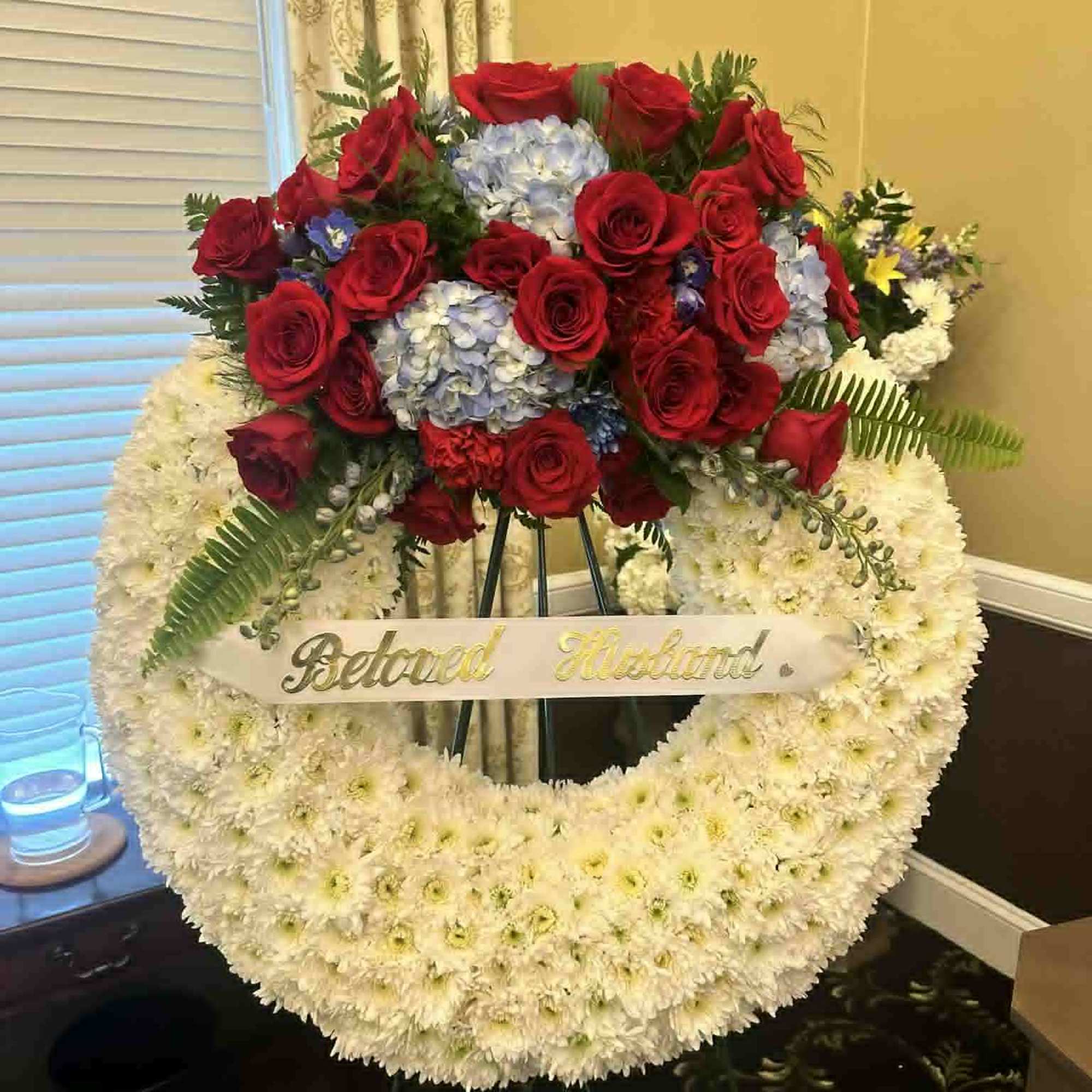 Large floral wreath with red roses and white flowers on an easel