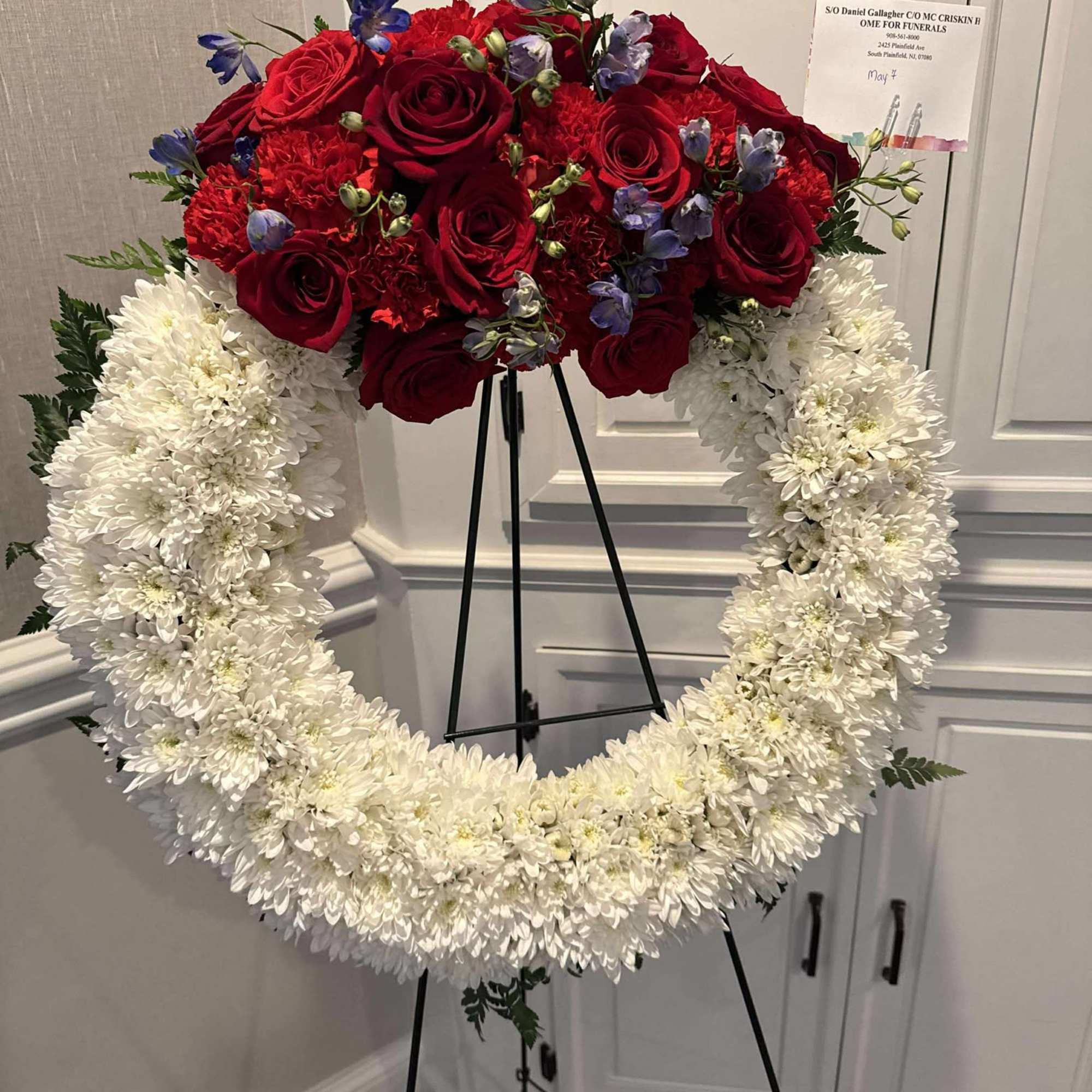 Standing floral wreath with red roses and white chrysanthemums on an easel