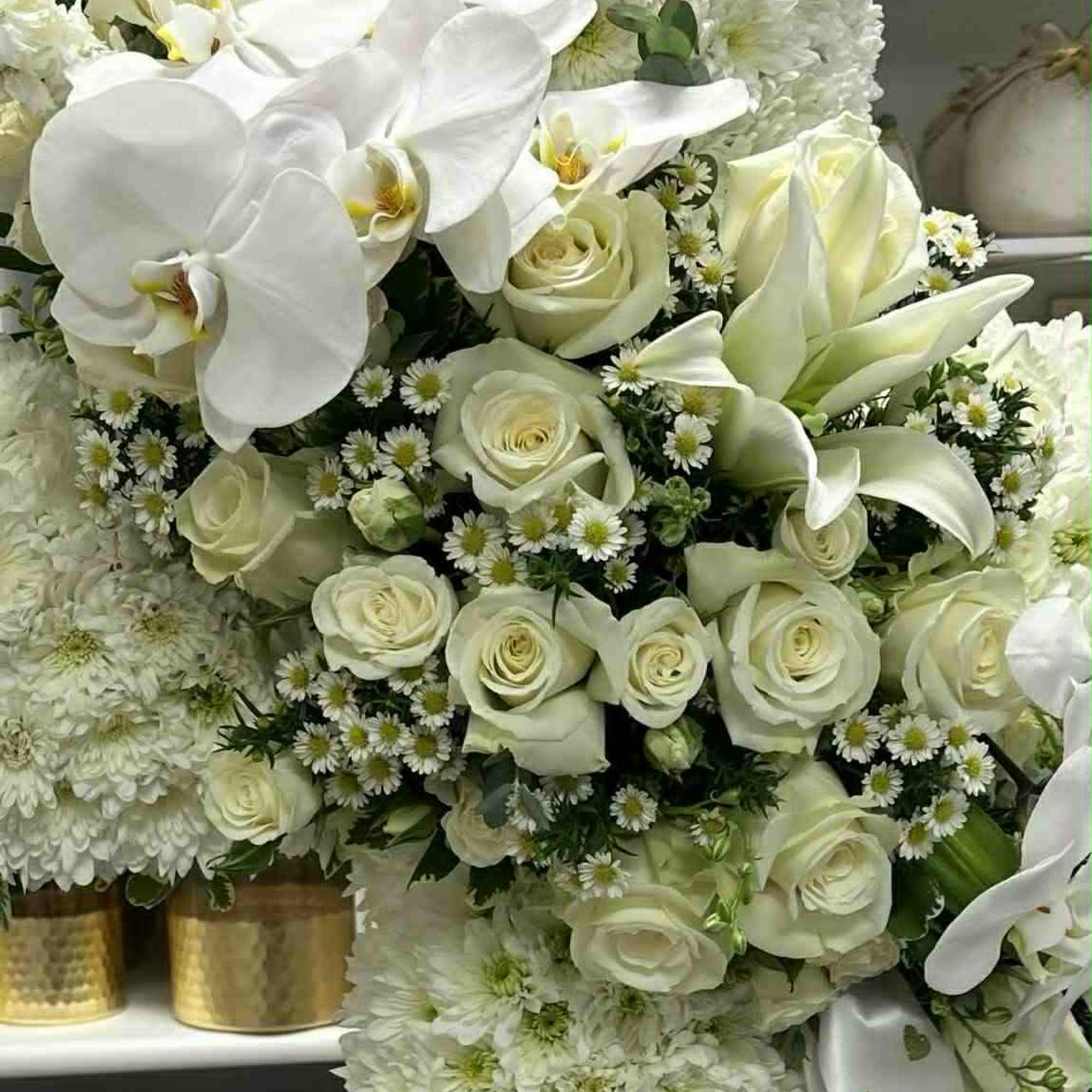 White floral arrangement with roses, orchids, and chrysanthemums