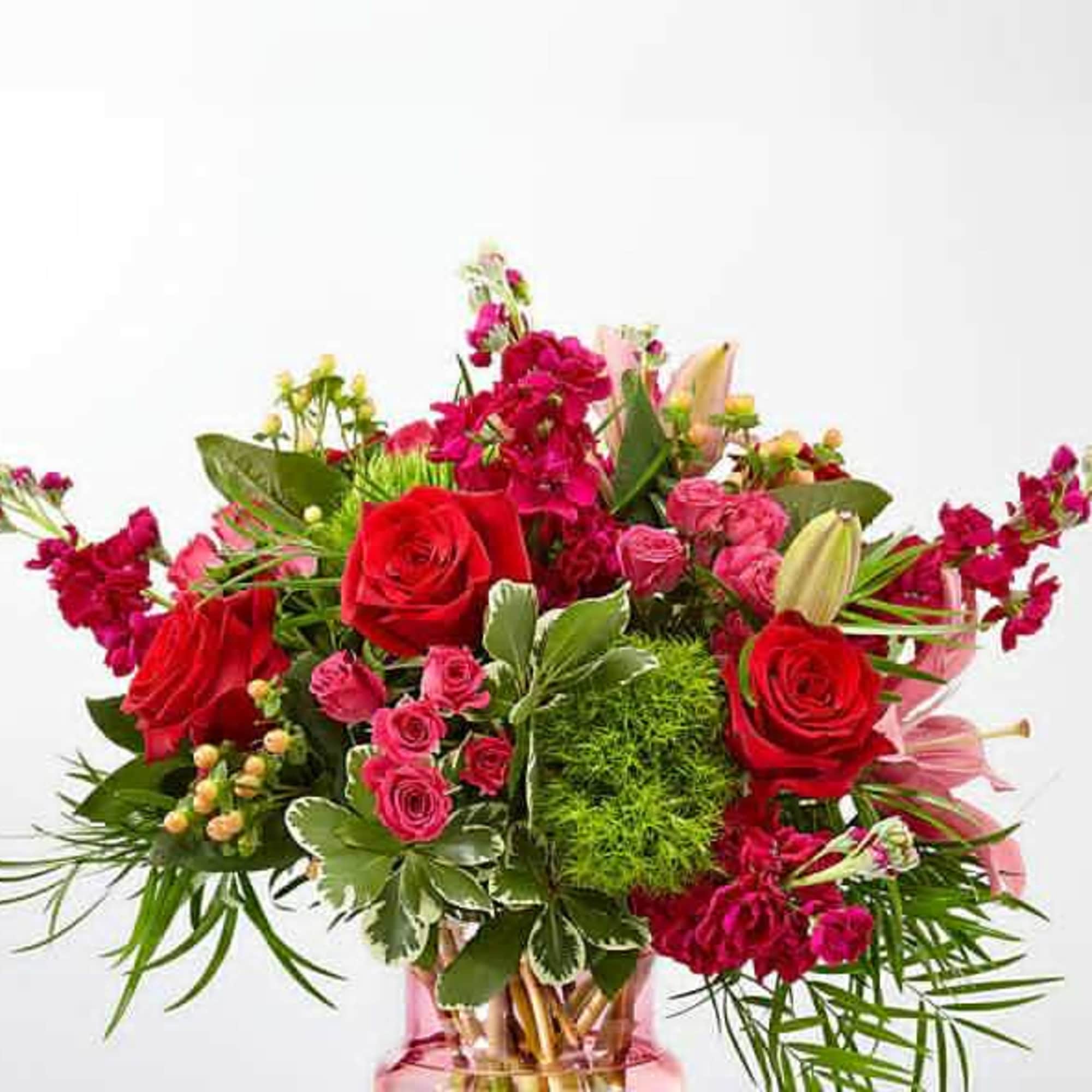Bouquet of red roses and pink flowers in a glass vase