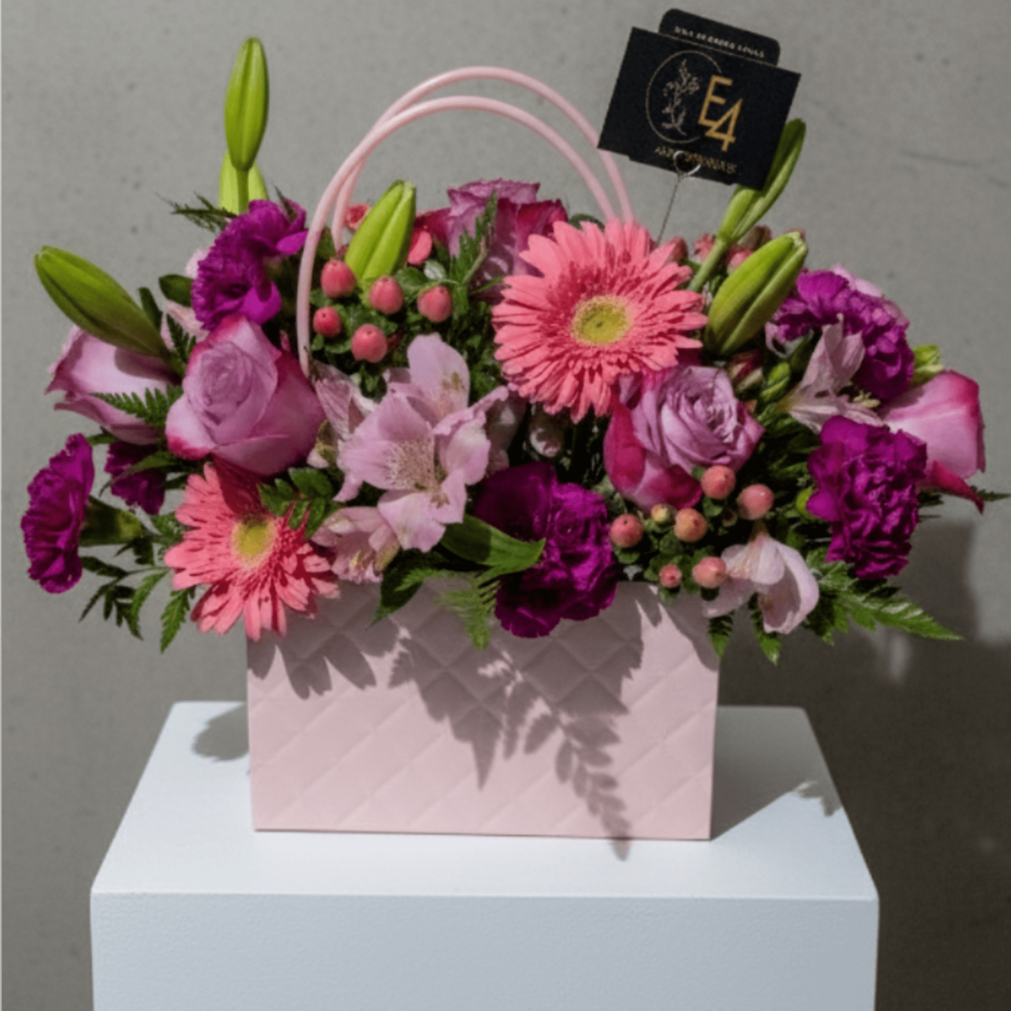 Pink and purple mixed flower arrangement in a pale pink gift bag
