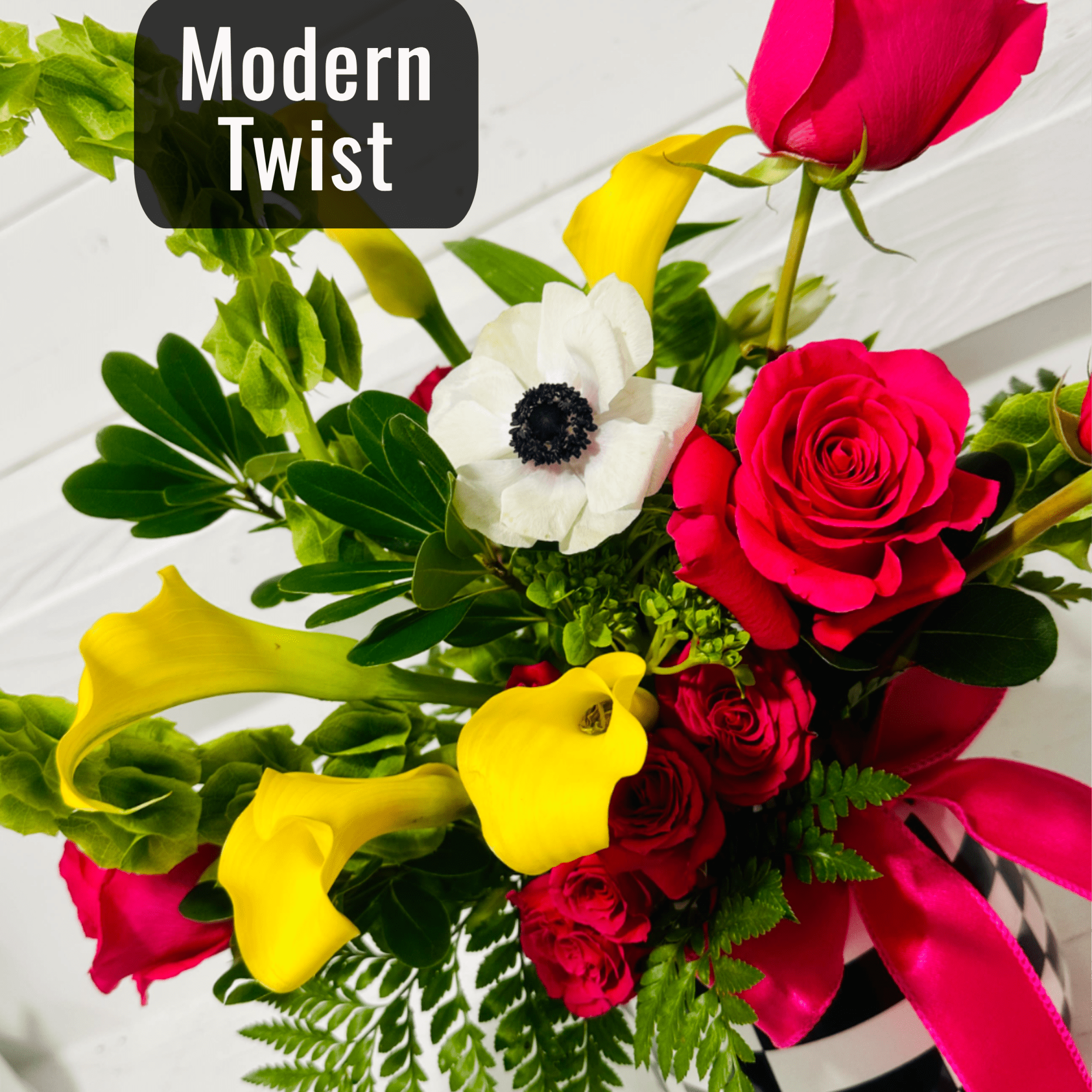 Bouquet of pink roses, yellow calla lilies, and a white anemone in a striped vase