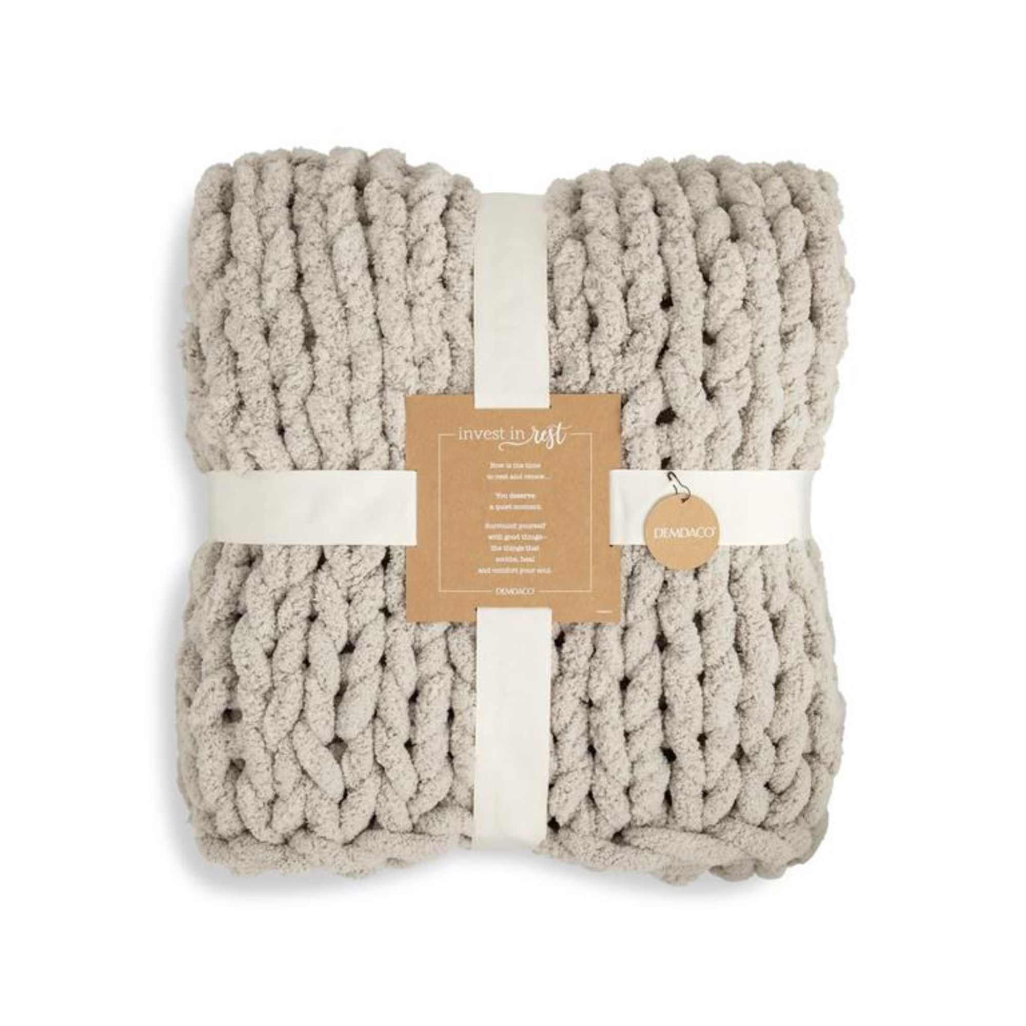 Folded chunky knit throw blanket wrapped with a paper band