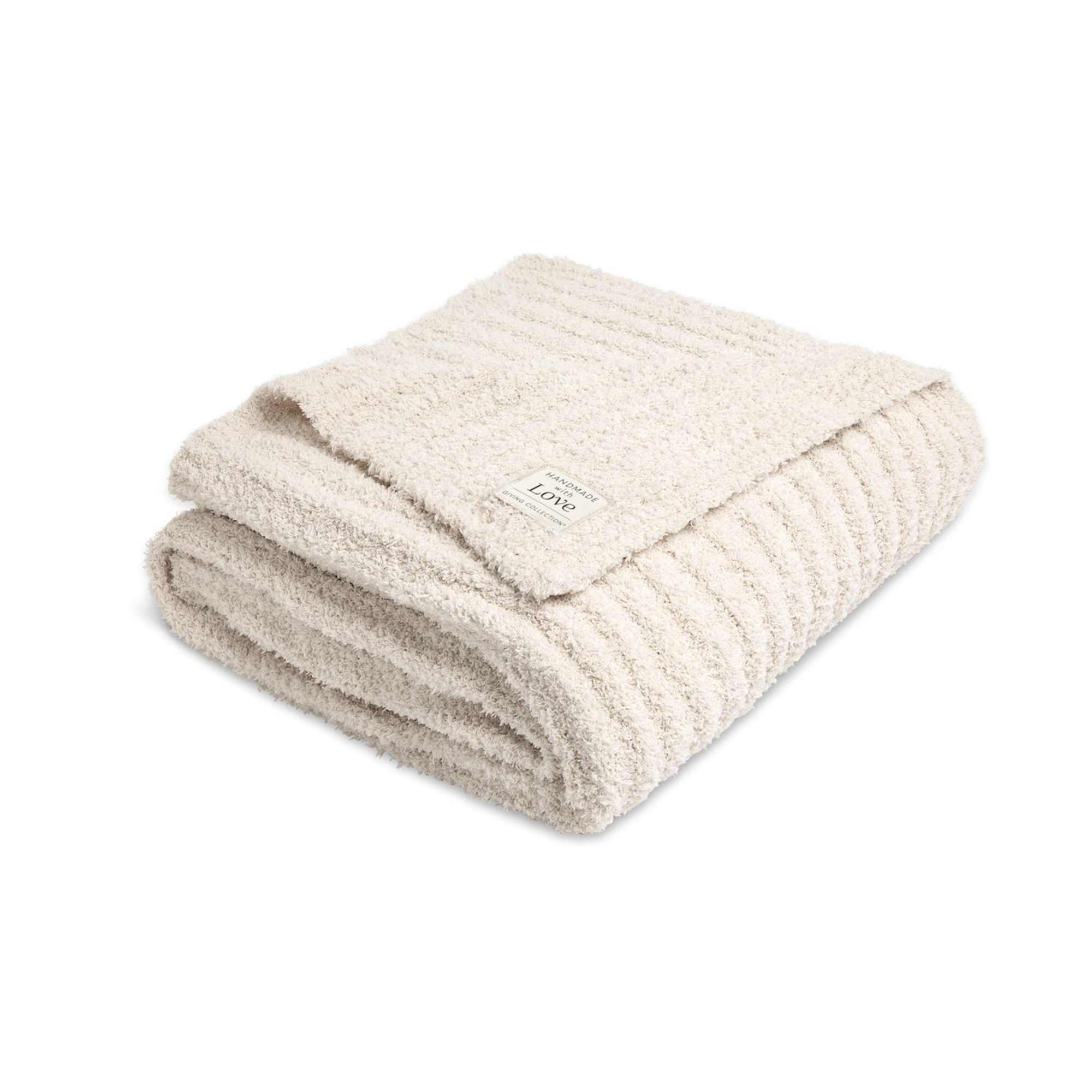 Folded cream-colored plush blanket with a small label