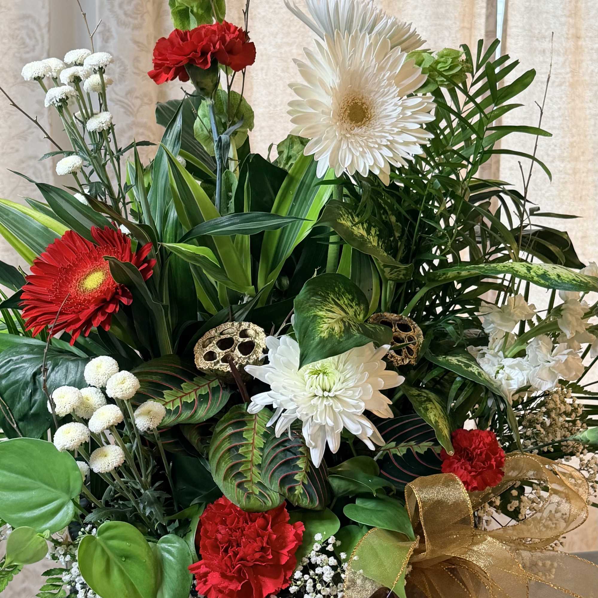 Mixed floral arrangement with red and white blooms in a dark container