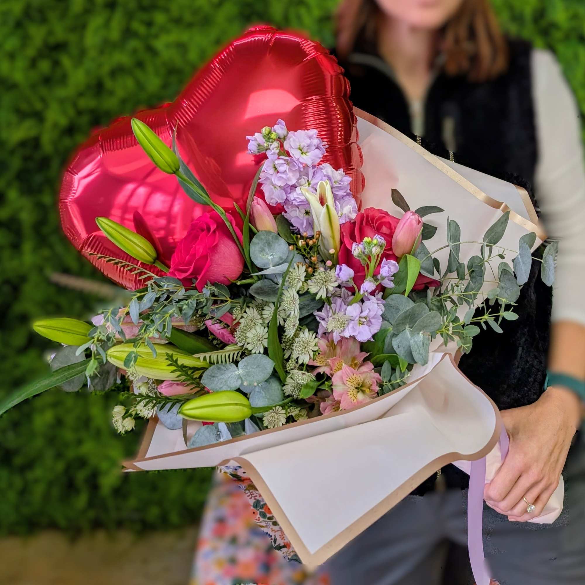 Bouquet of pink and lavender flowers with red heart balloons