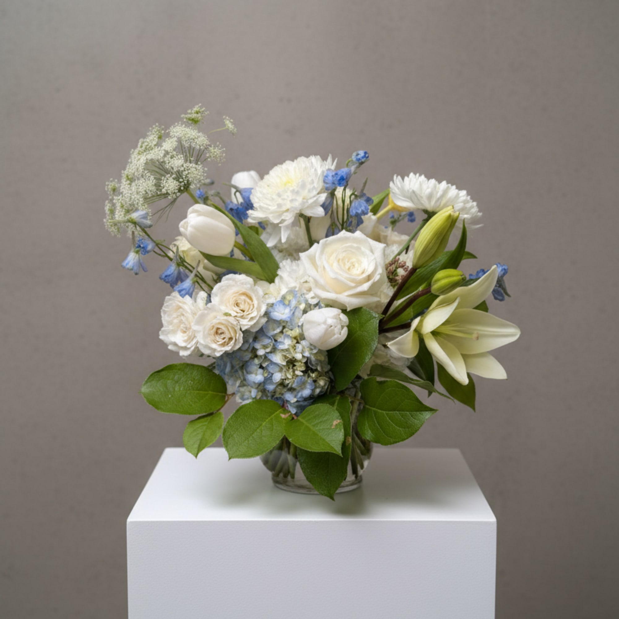 White and blue floral bouquet in a clear glass vase