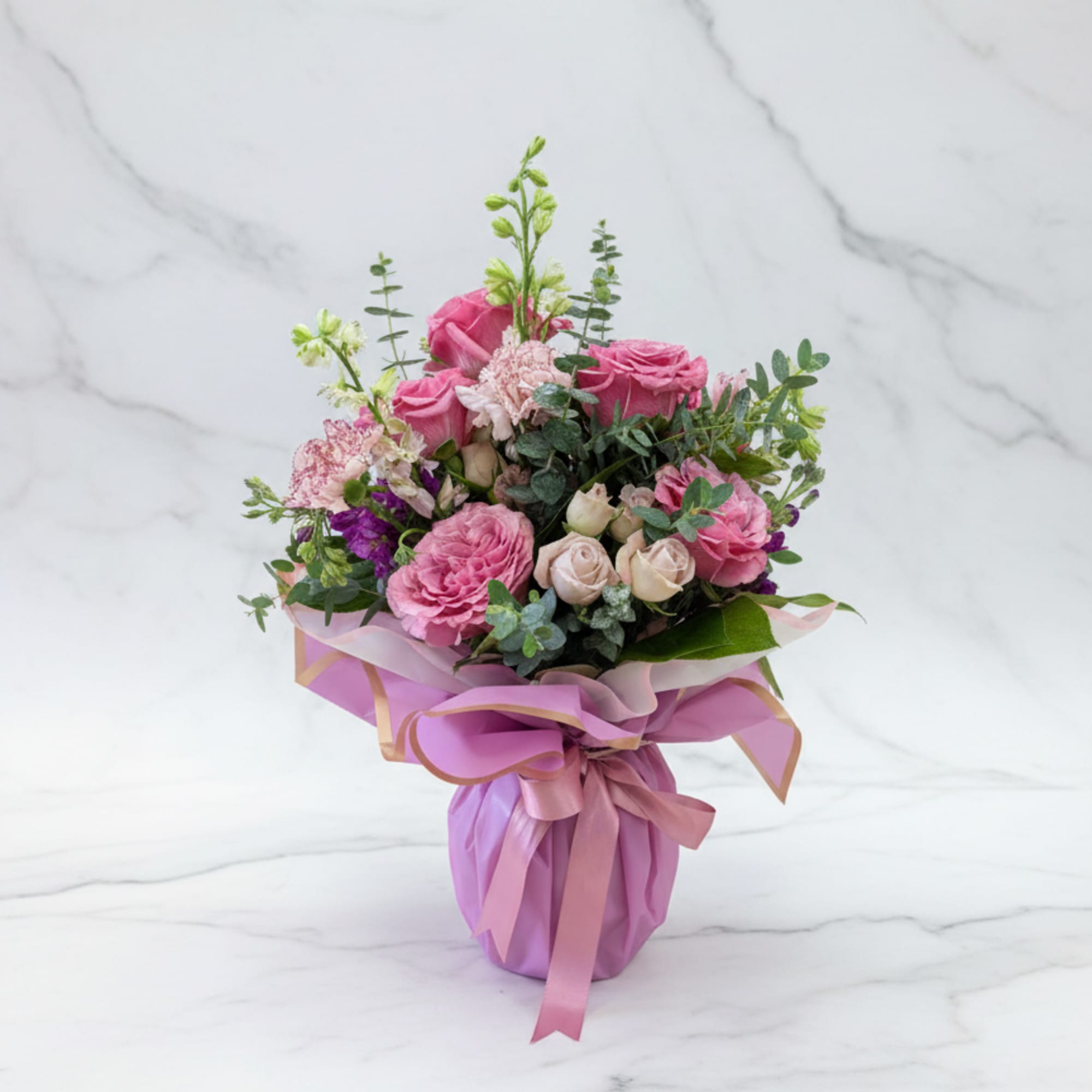 Pink rose bouquet wrapped in lavender paper with a ribbon
