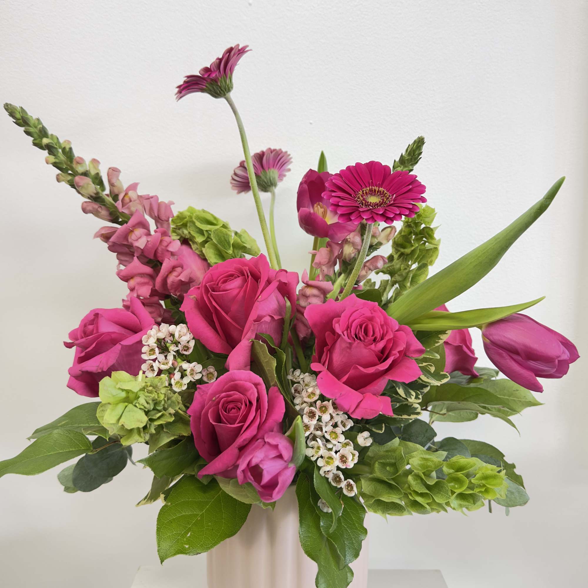 Pink roses and gerbera daisies in a pale vase