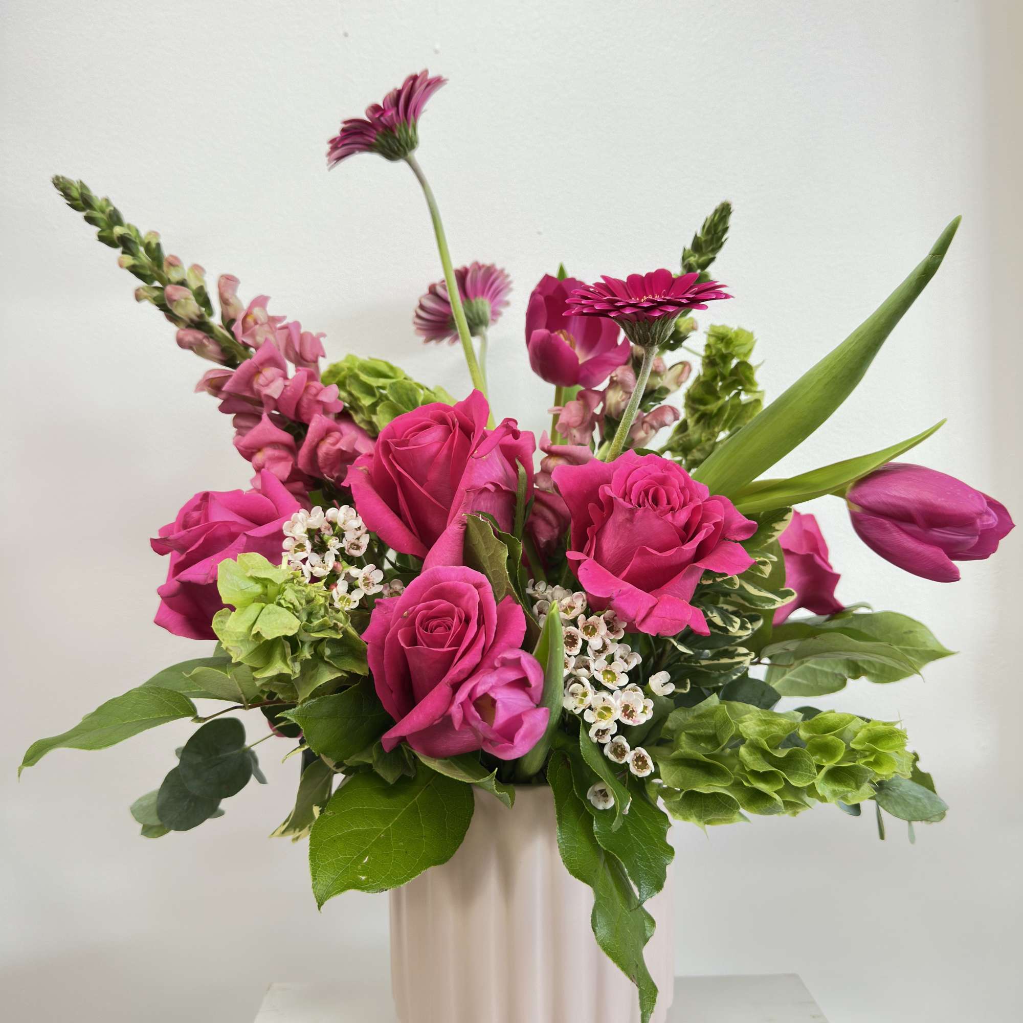 Pink roses and tulips in a pale vase