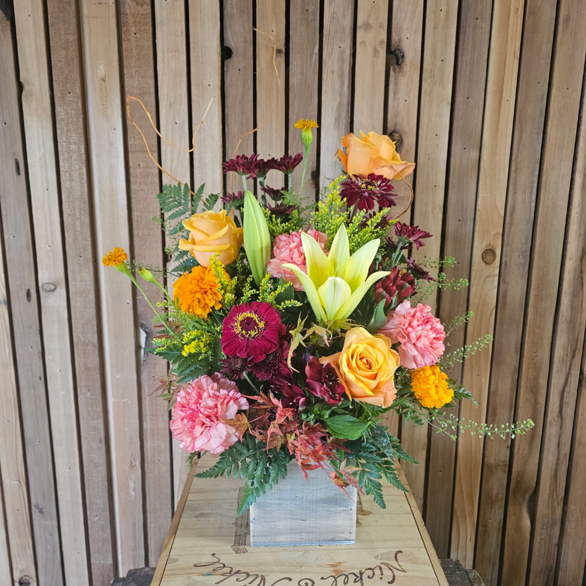 Mixed bouquet with roses, lilies, carnations, and chrysanthemums in a square vase
