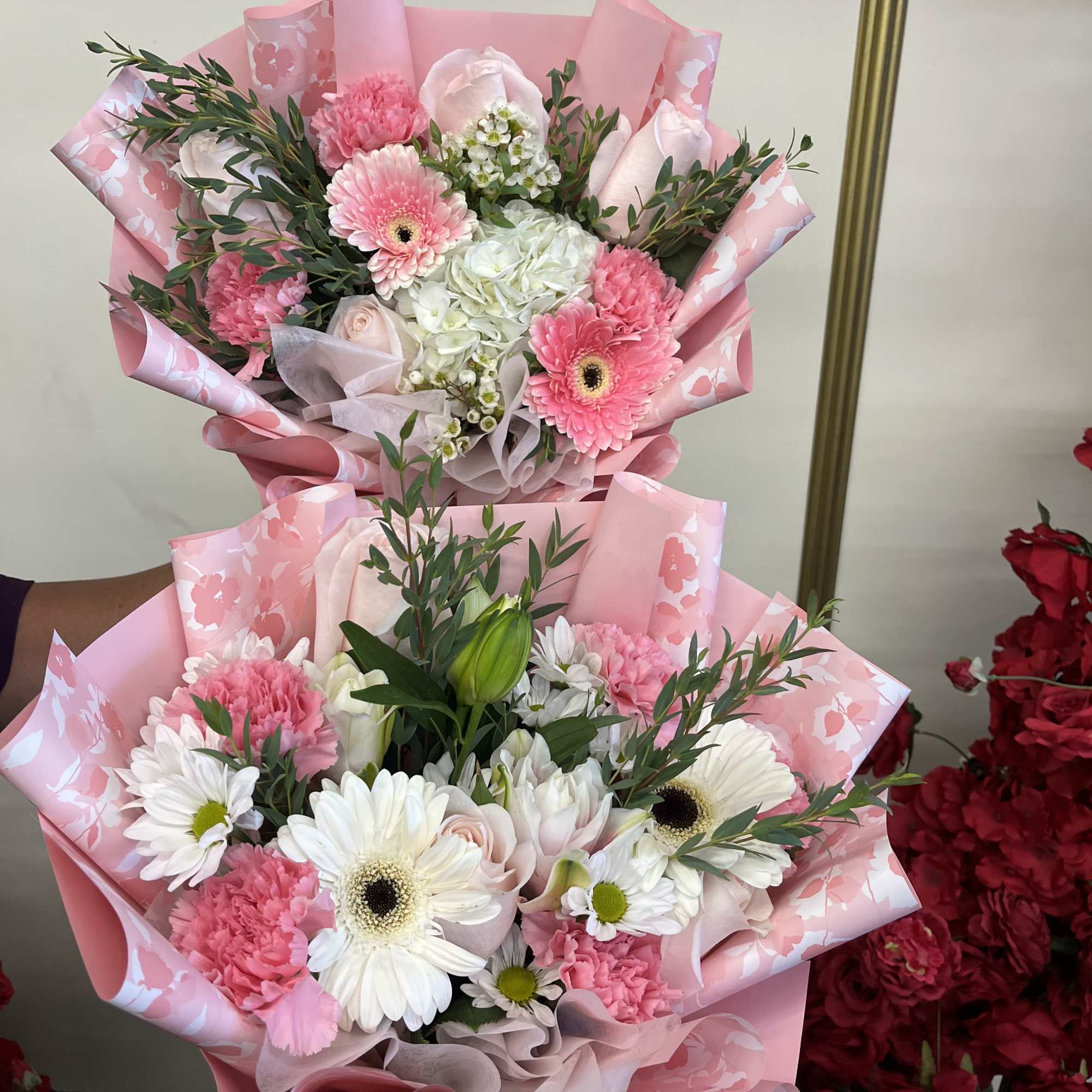 Two pink and white mixed bouquets wrapped in pink paper