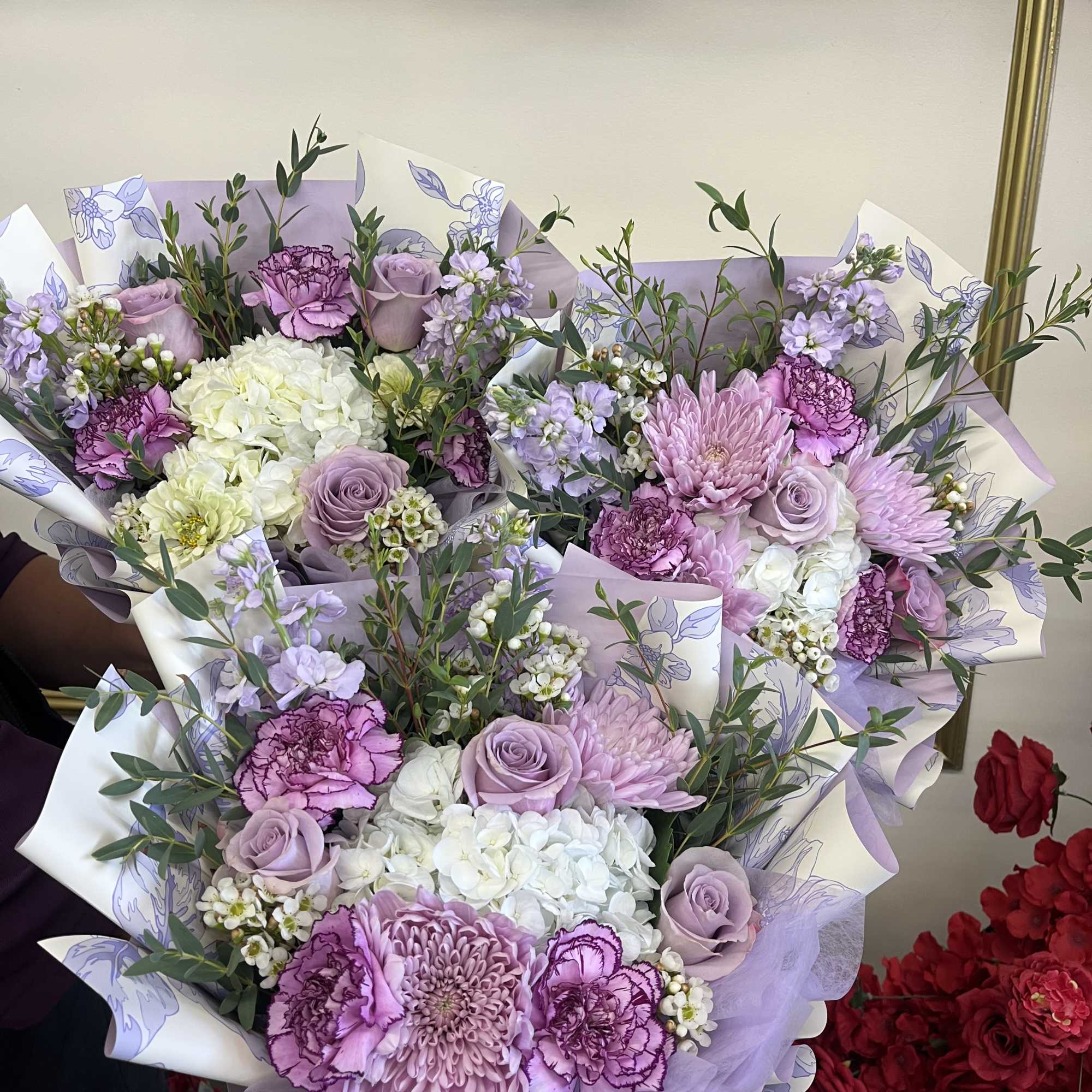 Three lavender and white mixed bouquets wrapped in lilac paper