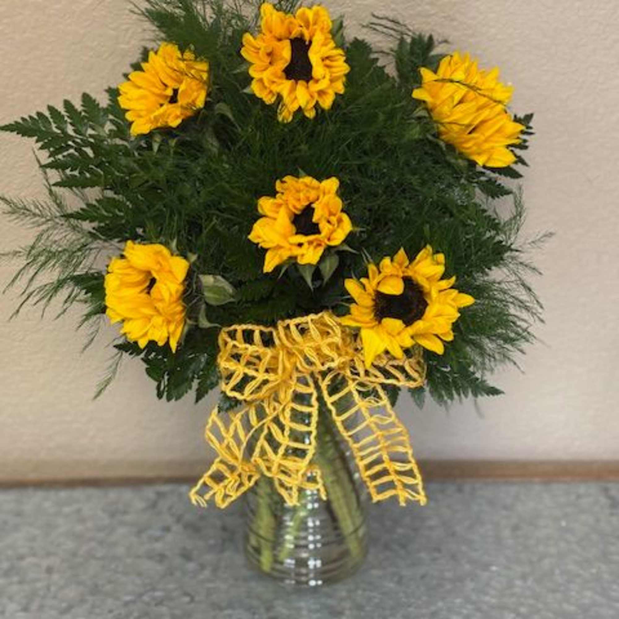 Sunflower arrangement in a glass vase with a yellow ribbon