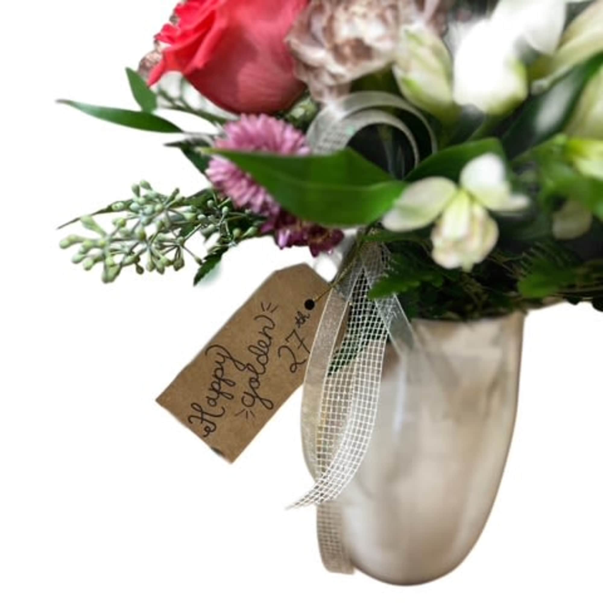 Bouquet of pink and white flowers in a metallic vase with a ribbon tag