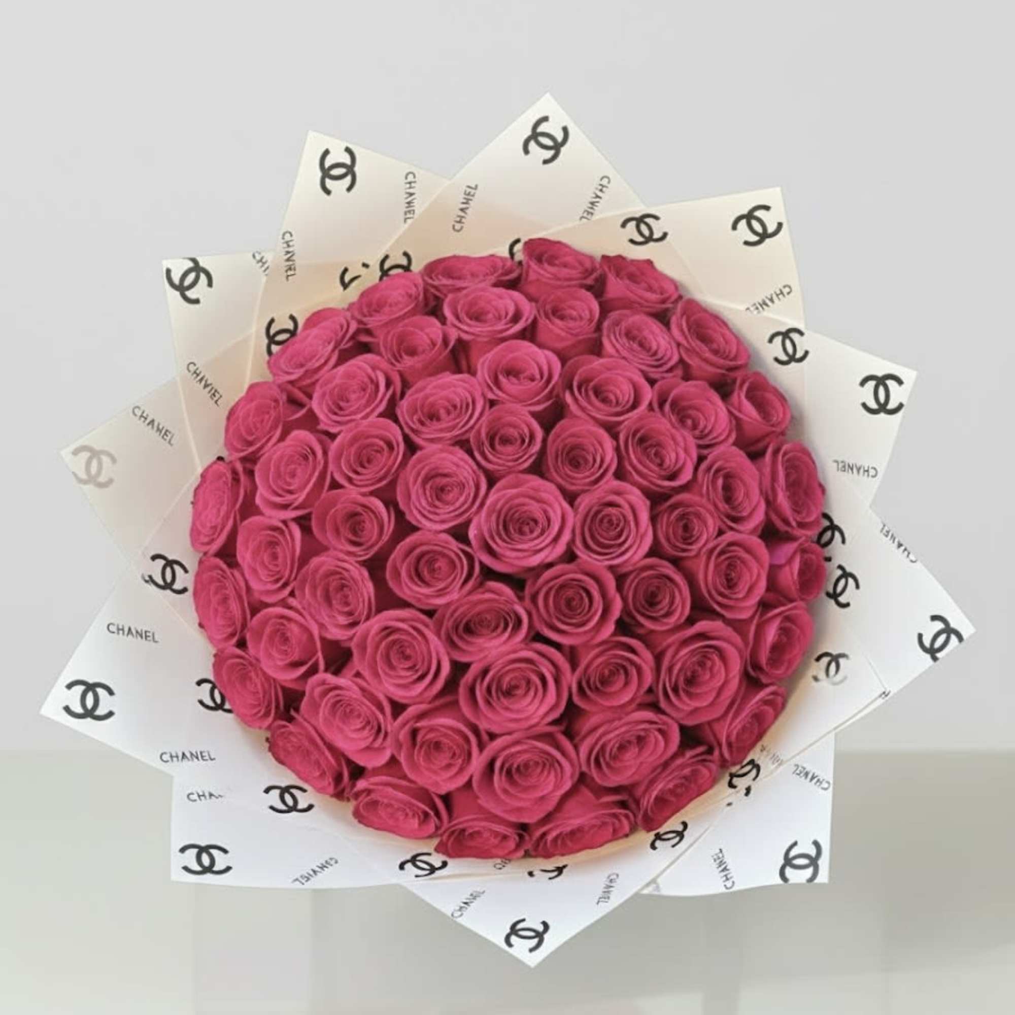 Bouquet of bright pink roses wrapped in Chanel-logo paper