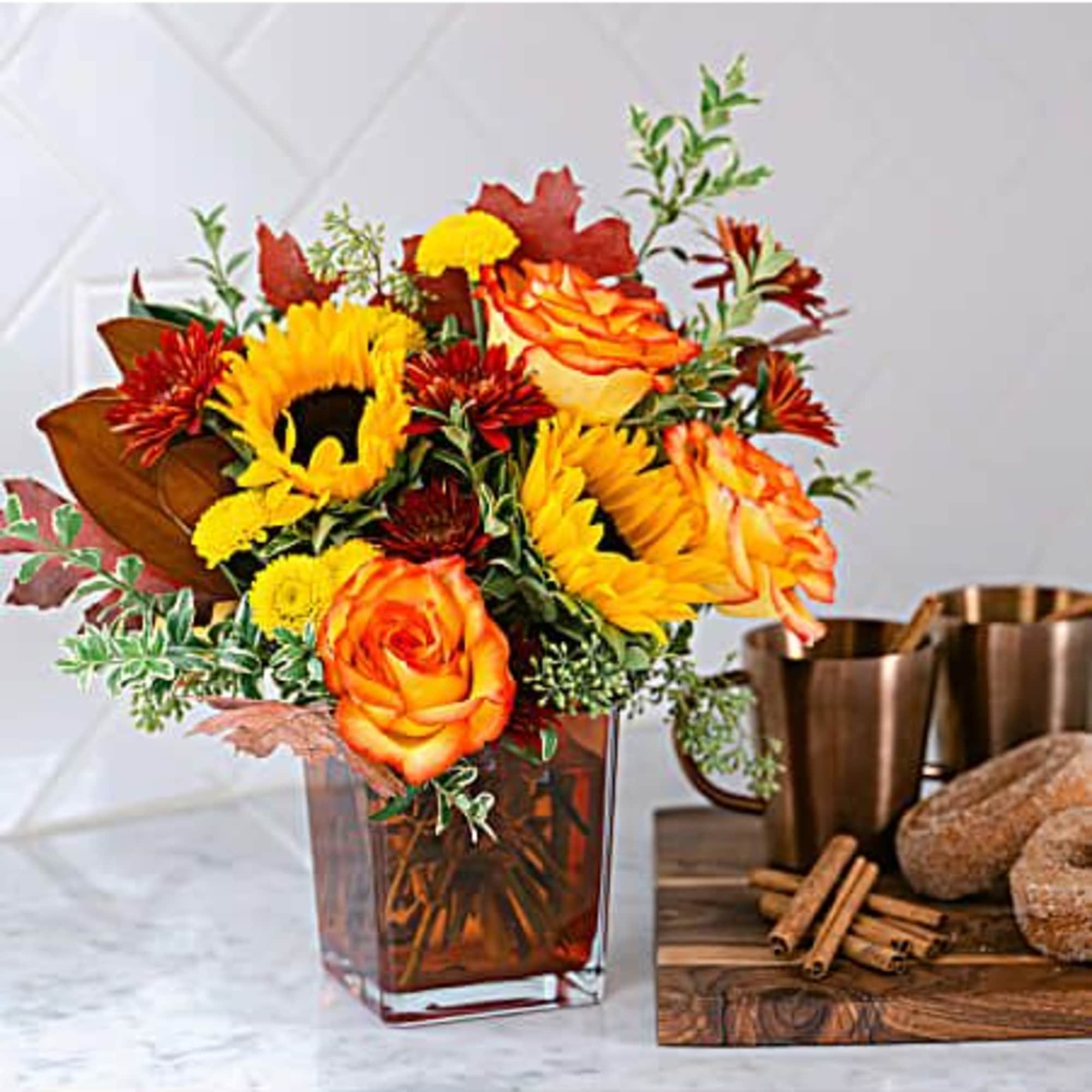 Orange and yellow flower arrangement in a square glass vase