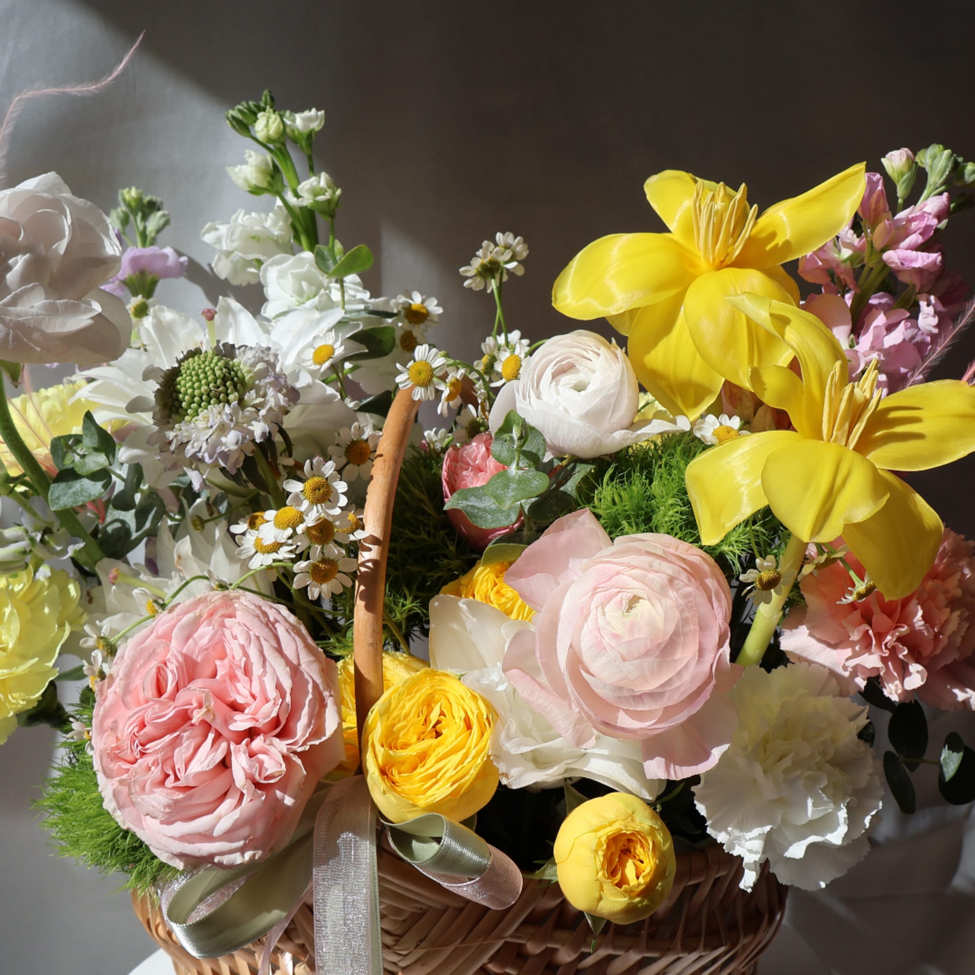 Basket of pastel flowers with yellow lilies and pink roses