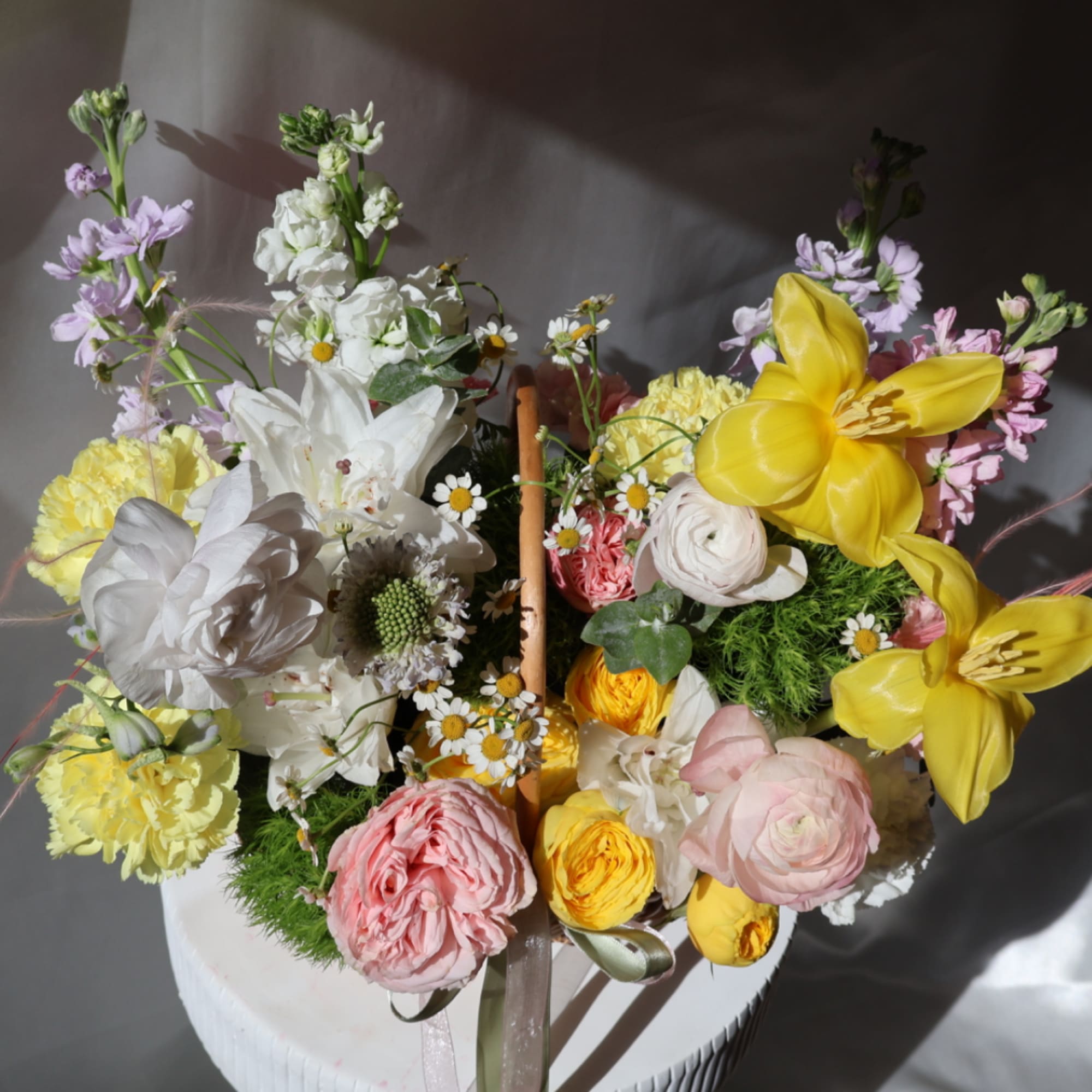 Mixed bouquet with yellow lilies, white blooms, and pink flowers in a basket