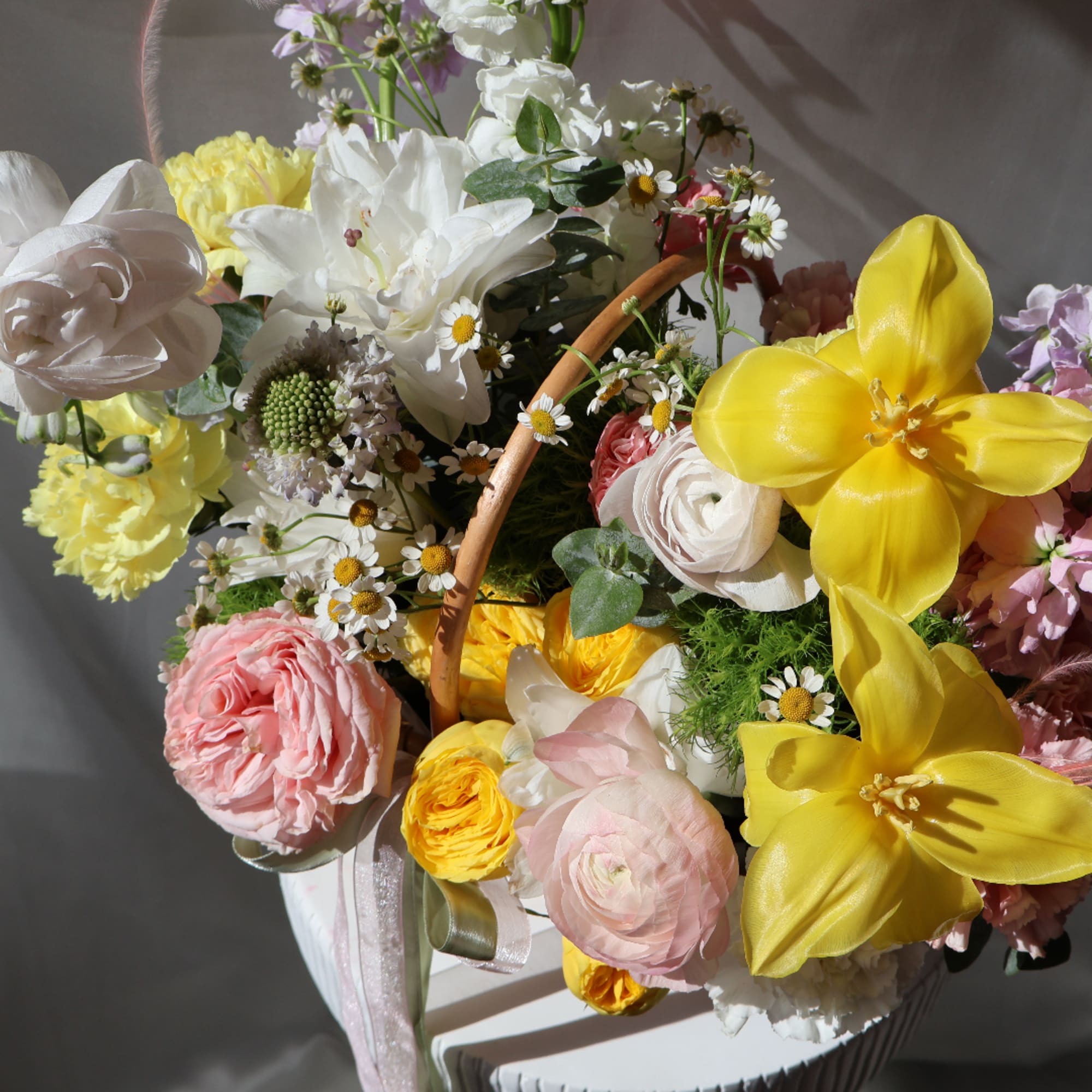 Basket of mixed pastel flowers with bright yellow blooms