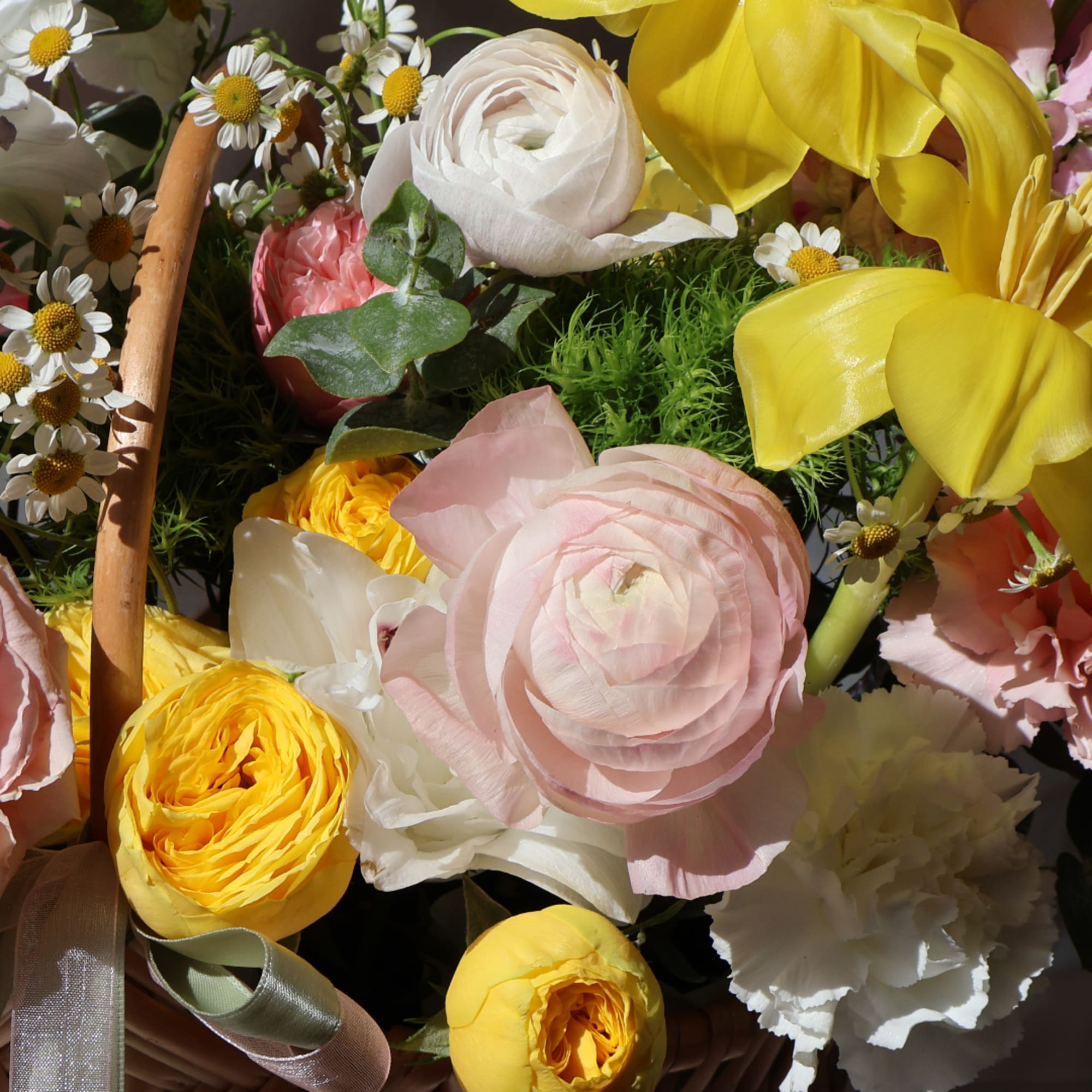 Basket of pastel flowers with yellow and pink blooms