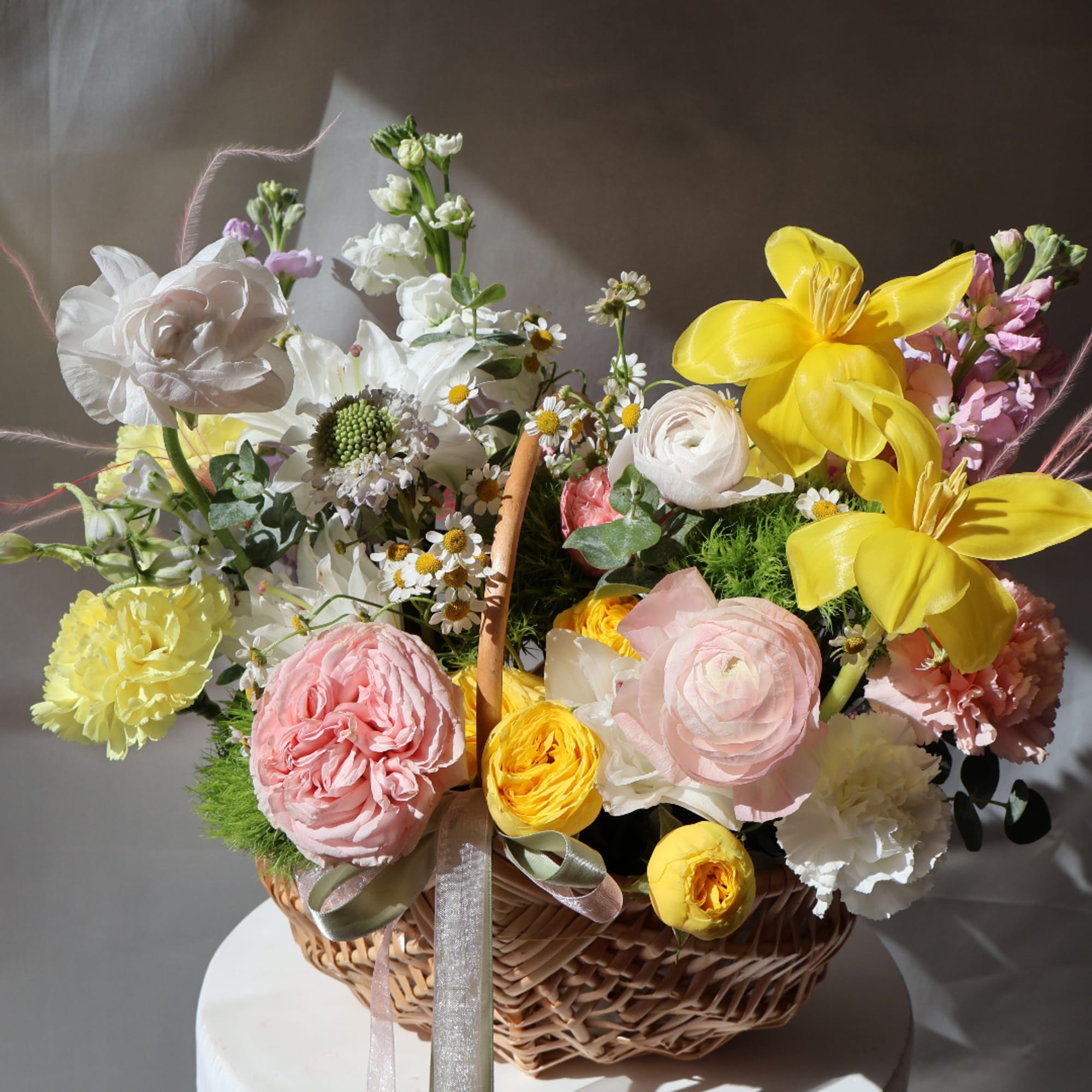 Basket of mixed flowers with yellow lilies, pink roses, and white blooms