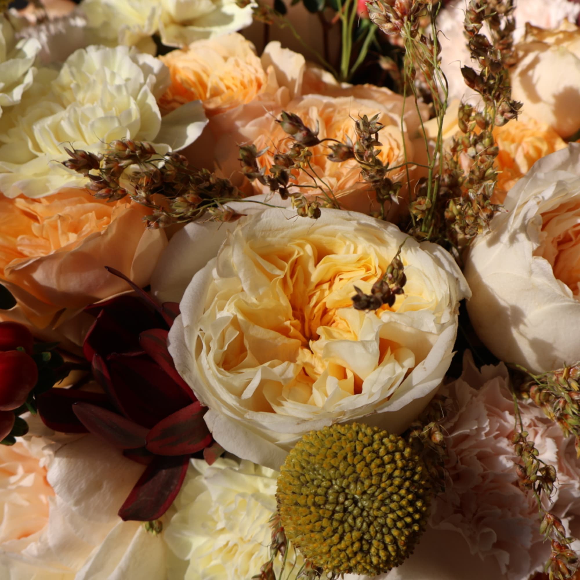 Close-up bouquet of cream and peach roses with dried accents