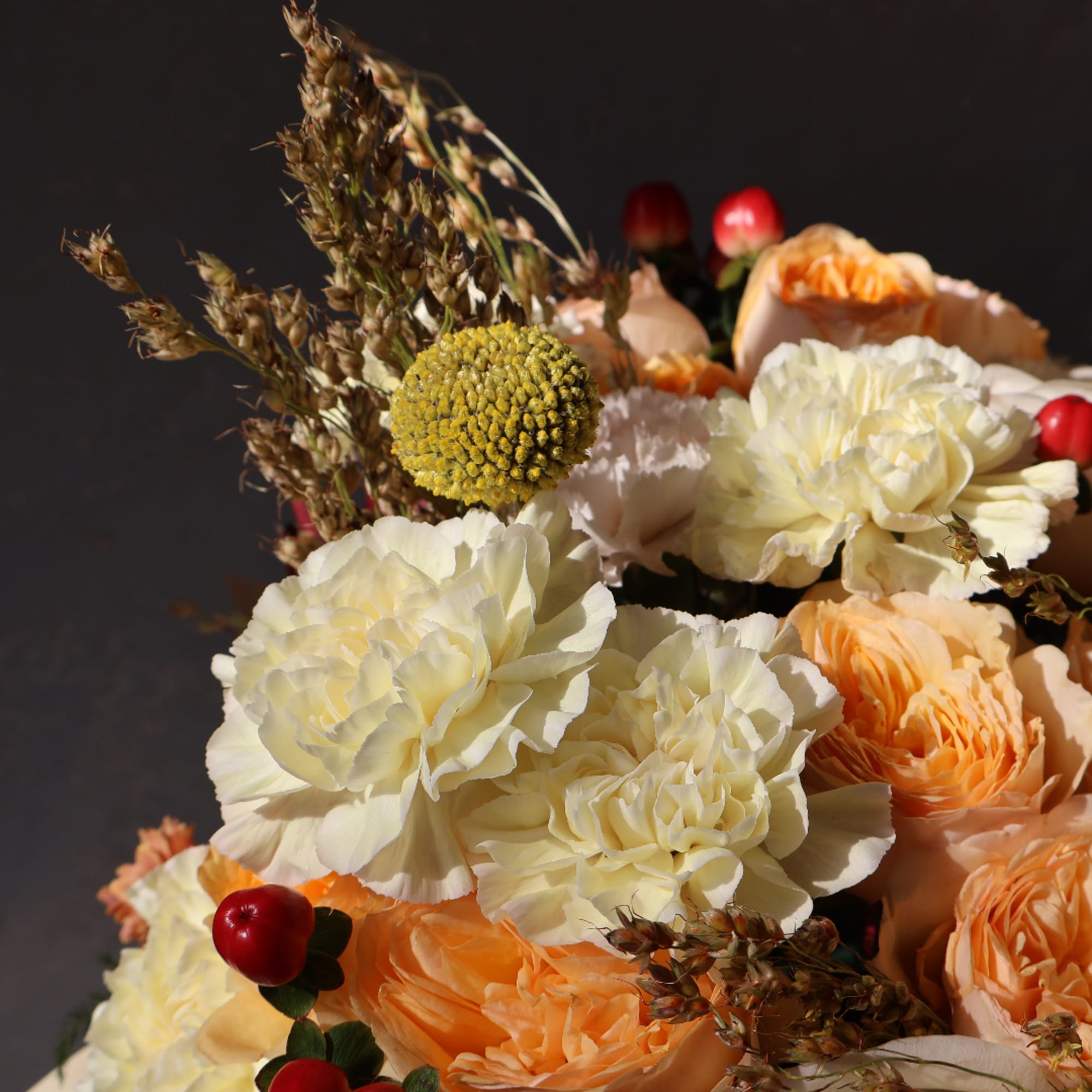 Bouquet of cream and peach flowers with red berry accents