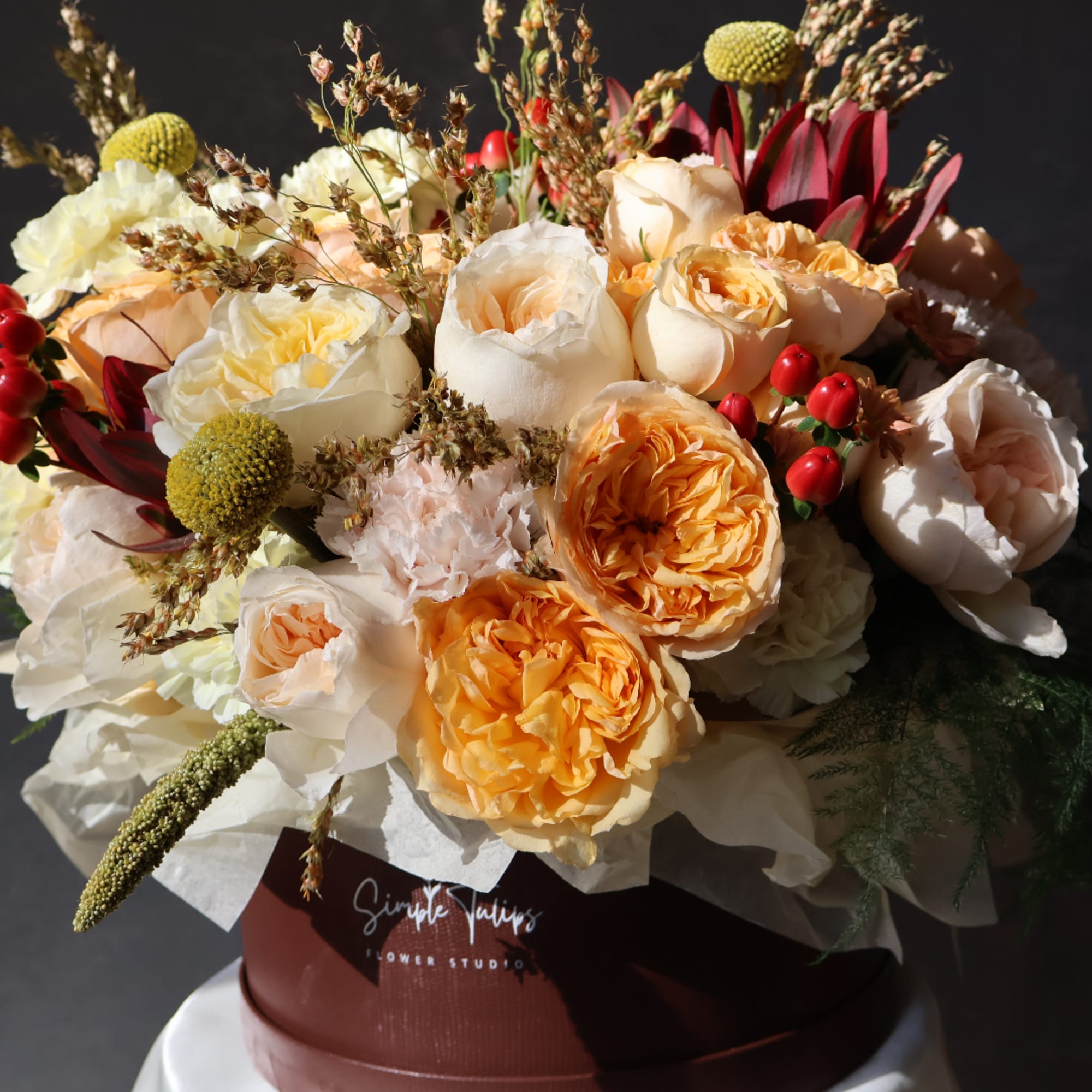 Bouquet of peach and white roses in a burgundy box